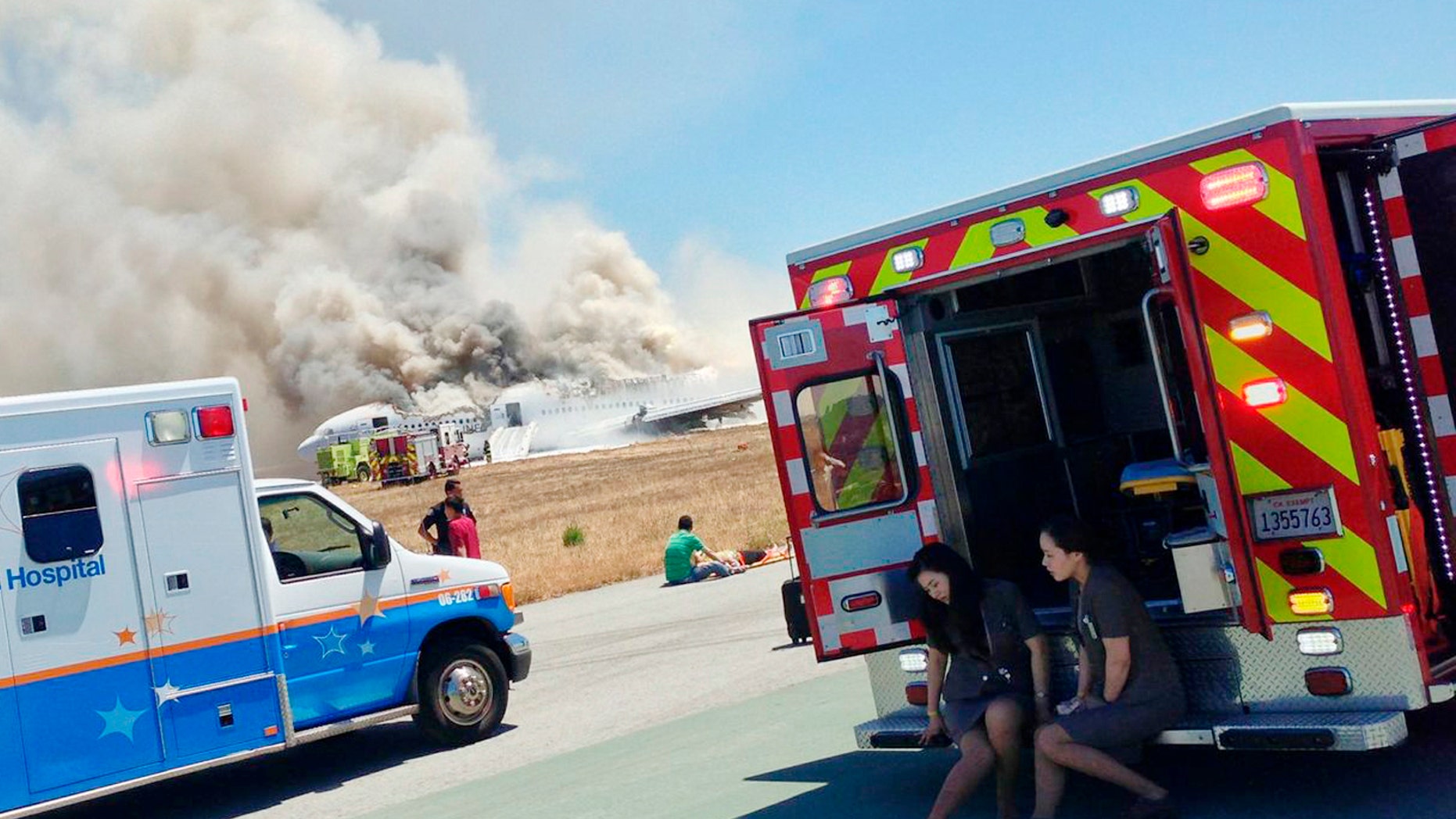 Asiana Airlines flight attendants and rescued passengers rest on the runway after flight 214 crash landed at San Francisco International Airport in California July 6, 2013.