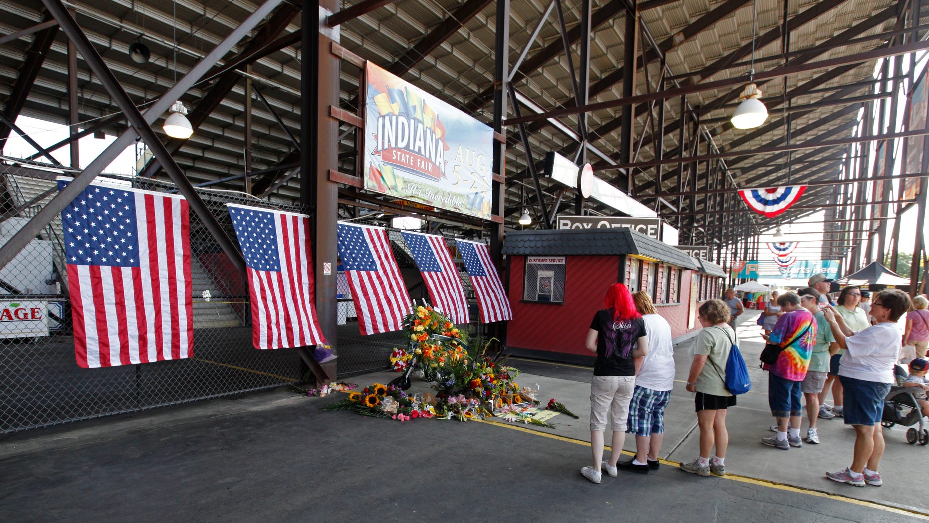August 16: Patrons walk past a memorial in front of the Grandstand at the Indiana State Fair in Indianapolis. The memorial is set-up for those who were killed when a stage collapsed Saturday night. As the Indiana State Fair reopened, questions lingered about the structure's safety.