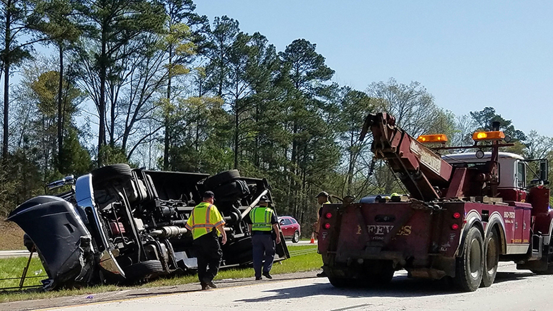 Police officers and emergency workers examine the scene of the accident scene Thursday morning, April 5, 2018, after a tour bus heading to the Masters golf tournament overturned along Interstate 20 near Augusta, Ga. Authorities say at least a dozen people were injured and the bus driver Steven Hoppenbrouwer was charged with DUI. (Joe Hotchkiss/The Augusta Chronicle via AP)