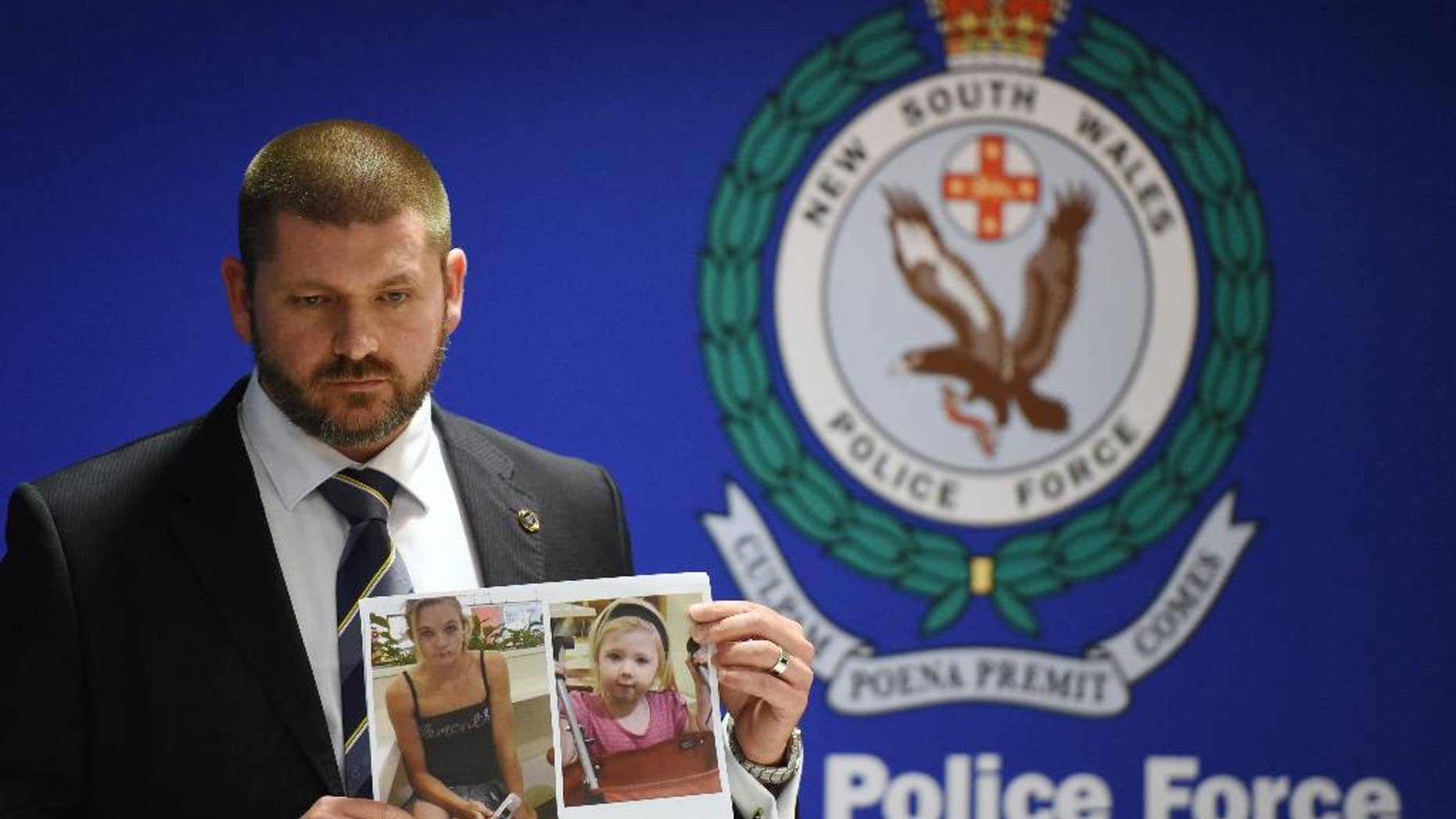 Police Detective Inspector Jason Dickinson holds up a photo of Karlie Jade Pearce-Stevenson and her daughter Khandalyce Kiara Pearce, during a press conference in Sydney, Wednesday, Oct. 21, 2015. A child whose decomposed body was found in a suitcase in southern Australia earlier this year is the daughter of a woman whose skeletal remains were found in 2010 in a forest 1,200 kilometers (750 miles) away, police said. (Dean Lewins/AAP Image via AP) NO ARCHIVING, AUSTRALIA OUT, NEW ZEALAND OUT, PAPUA NEW GUINEA OUT, SOUTH PACIFIC OUT