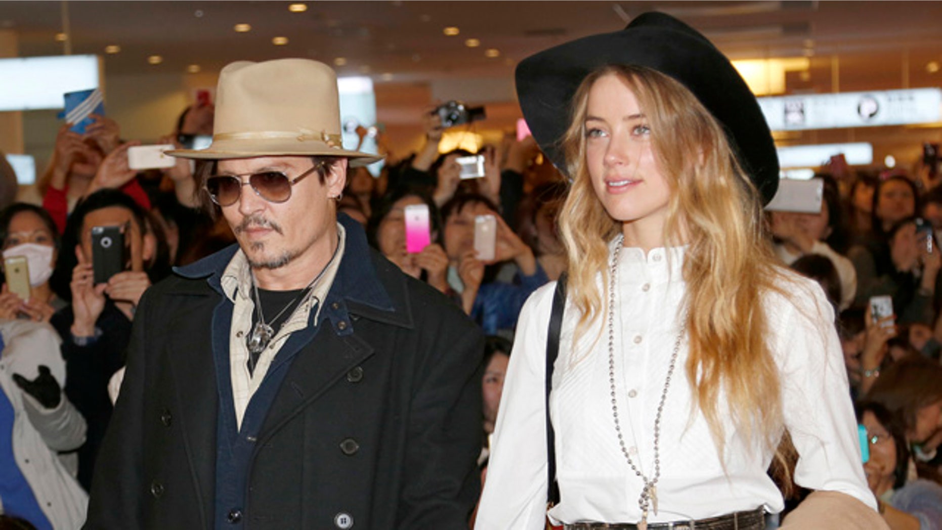FILE - In this Jan. 26, 2015 file photo, U.S. actor Johnny Depp and Amber Heard arrive at Haneda international airport in Tokyo to promote his latest film 'Mortdecai'. Heard has been charged with illegally bringing the couple's dogs to Australia. Prosecutors on Thursday, July 16, 2015 said that Heard was charged this week with two counts of illegally importing Pistol and Boo into Australia and one count of producing a false document. (AP Photo/Shizuo Kambayashi, File)