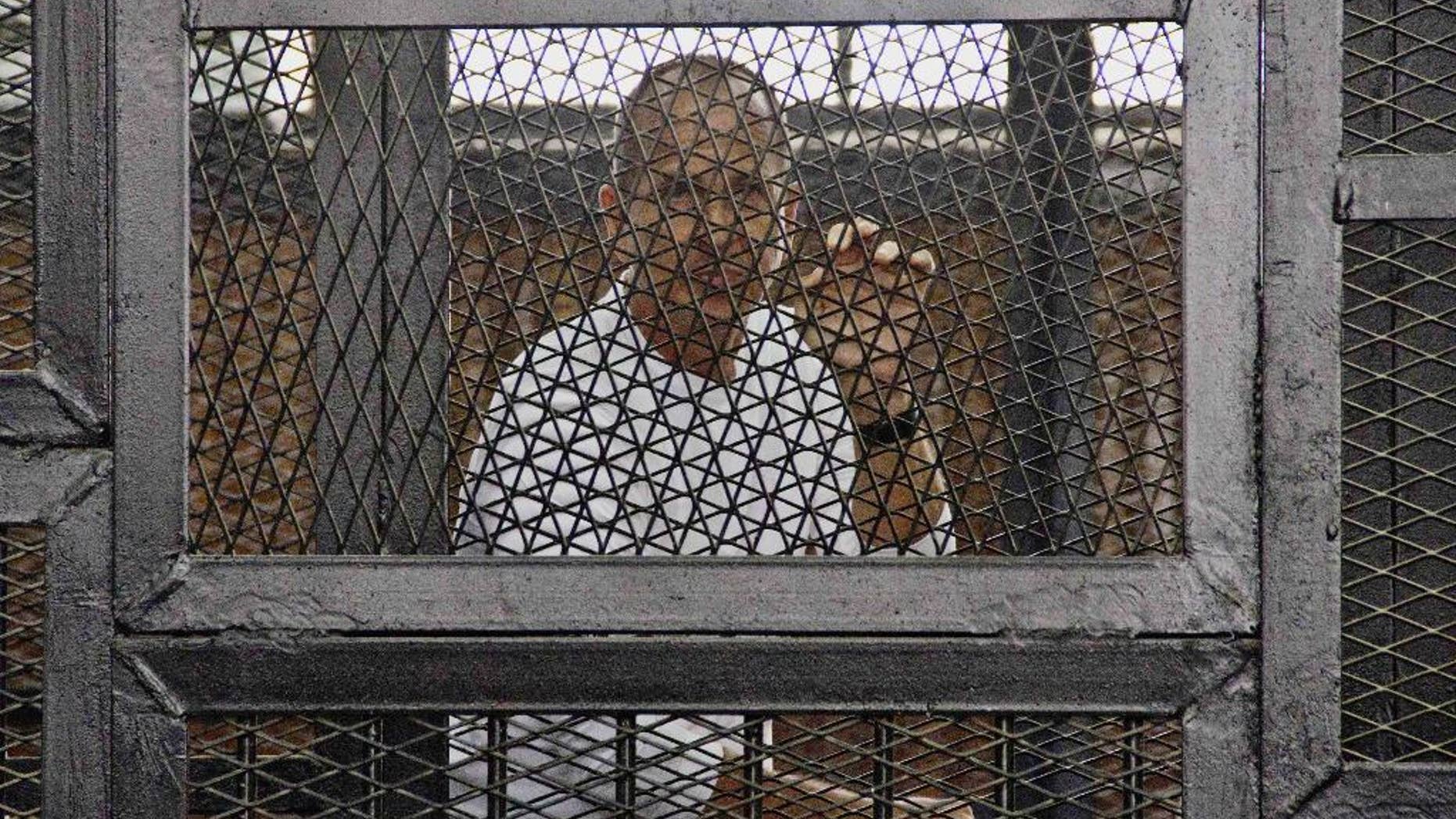 FILE - In this May 3, 2014 file photo, Al-Jazeera's award-winning Australian correspondent Peter Greste appears in a defendants' cage in the Police Academy courthouse along with several other defendants during a trial on terror charges in Cairo, Egypt. Australian Prime Minister Tony Abbott said Monday, June 23 that he told Egyptian President Abdel Fatah al-Sisi that the jailed Australian journalist is innocent of charges that he supported the outlawed Muslim Brotherhood. (AP Photo/Hamada Elrasam, File)