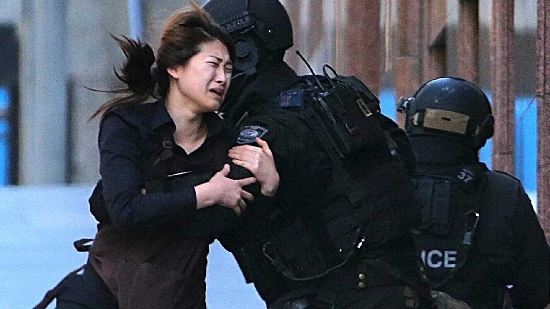 In this Dec. 15, 2014 file photo, a hostage runs to armed tactical response police officers for safety after she escaped from a cafe under siege at Martin Place in the central business district of Sydney, Australia. For a country of just 24 million that is thousands of miles from Syria and Iraq, Australia has been unusually fertile ground for Islamic State recruiters.