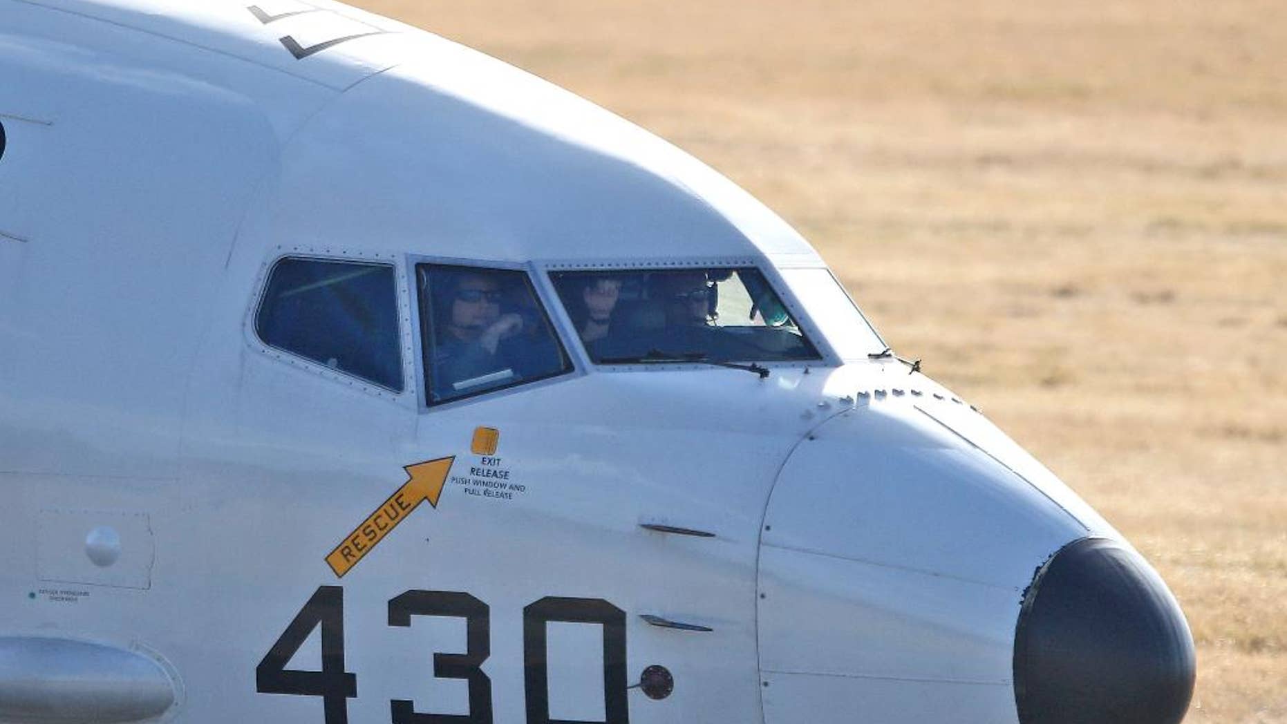 FILE - In this April 5, 2014 file photo, pilots look out of a window from the cockpit in a U.S. Navy P-8 Poseidon plane as it taxies to the end of the runway to take off from Perth Airport on route to conduct search operations for missing Malaysia Airlines Flight MH370 in southern Indian Ocean, near the coast of Western Australia. Every day from the Perth airport and a nearby military base, about a dozen planes from several countries take flight to search for debris from missing Flight 370 _ so far without success. The U.S. Defense Department alone committed $7.3 million to the effort in the first month of the search, much of it spent on two U.S. Navy P-8 Poseidon planes that cost $4,000 per hour to fly. (AP Photo/Rob Griffith, File)