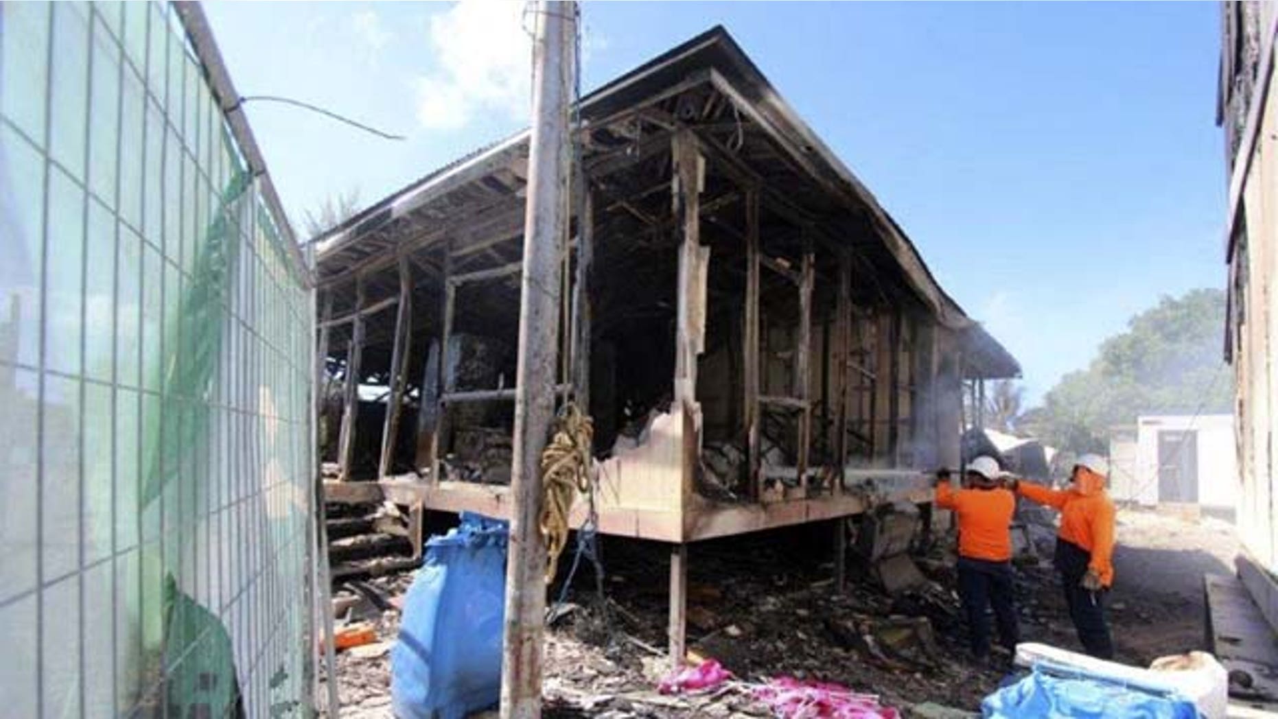 July 21, 2013: In this photo released by the Australian Department of Immigration and Citizenship workers extinguish the last smoldering embers after some 125 asylum seekers rioted at an Australian-run detention center in Nauru. (AP Photo)