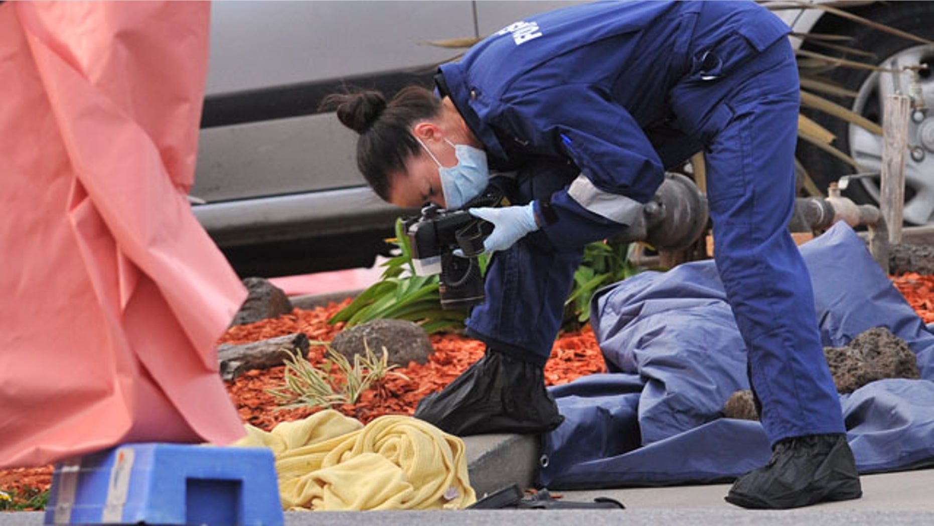 September 24, 2014: A forensic officer documents objects including a blanket at the scene of a fatal shooting at Endeavour Hills Police Station in Melbourne. (AP Photo/AAP Image, Julian Smith)