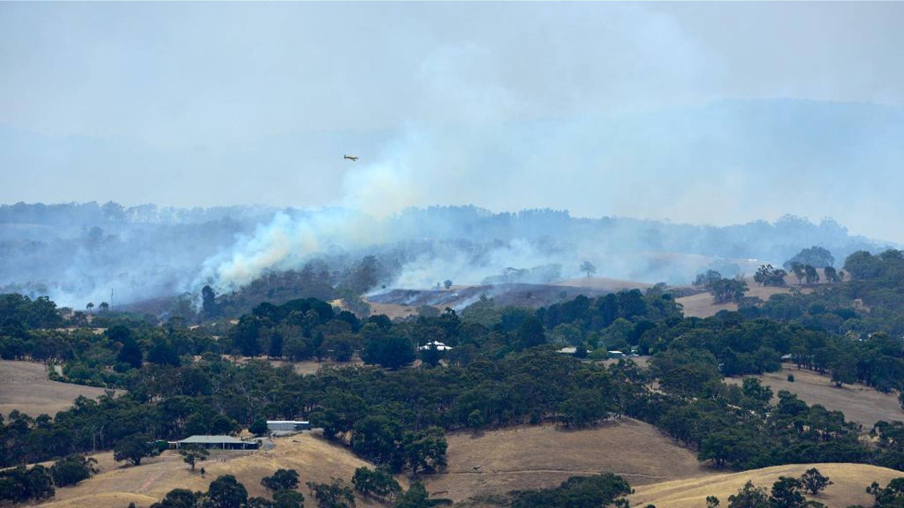 A plane flies over smoke from fires burring across the Adelaide Hills, near Adelaide, Australia, Saturday, Jan. 3, 2015. Thousands of Australians fled their homes as wildfires raged across the nation's south on Saturday, with firefighters struggling to contain the blazes as strong winds fanned the flames. (AAP IMAGE/ DAVID MARIUZ) EDITORIAL USE ONLY, AUSTRALIA OUT, NEW ZEALAND OUT, PAPUA NEW GUINEA OUT, SOUTH PACIFIC OUT, NO ARCHIVES