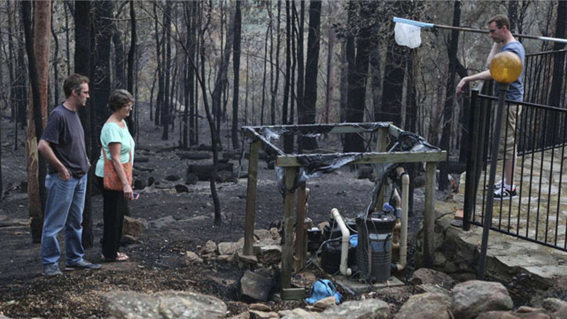October 22, 2013: Jennifer Schweinsberg and her sons David left, and Adam, right, walk around the ruins of their family home in Sunny Ridge Drive in Winmalee 40 miles from Sydney in Australia after a wildfire swept through the street burning it and several other homes on Oct 18, 2013. (AP Photo)