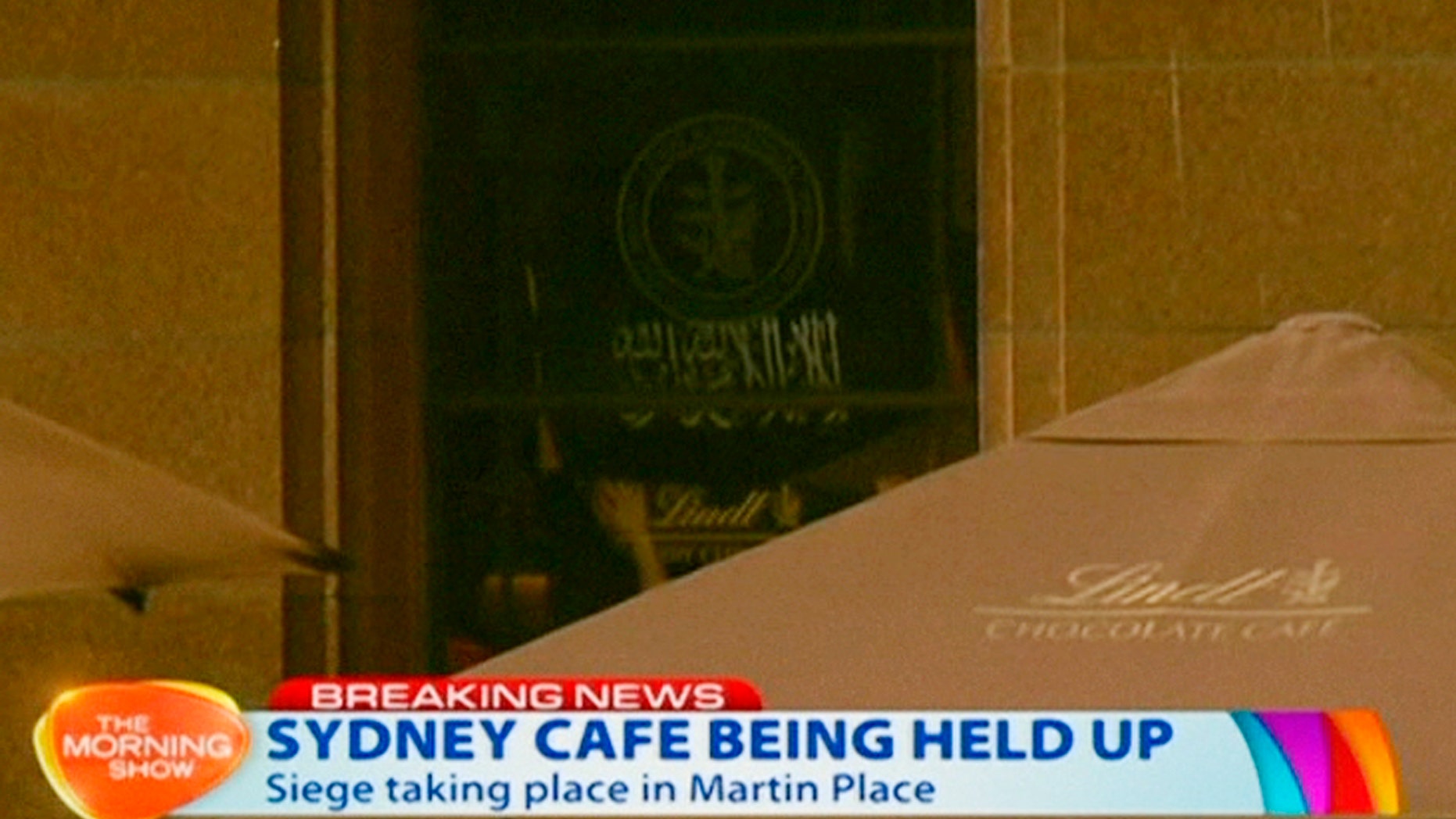 Dec. 15, 2014 - People holding up what appeared to be a black flag with white Arabic writing on it, inside a cafe in Sydney, Australia. A gunman took an unknown number of people hostage inside the downtown Sydney chocolate shop and cafe. The flag was believed to contain an Islamic declaration of faith. (still taken from Ch.7 video)