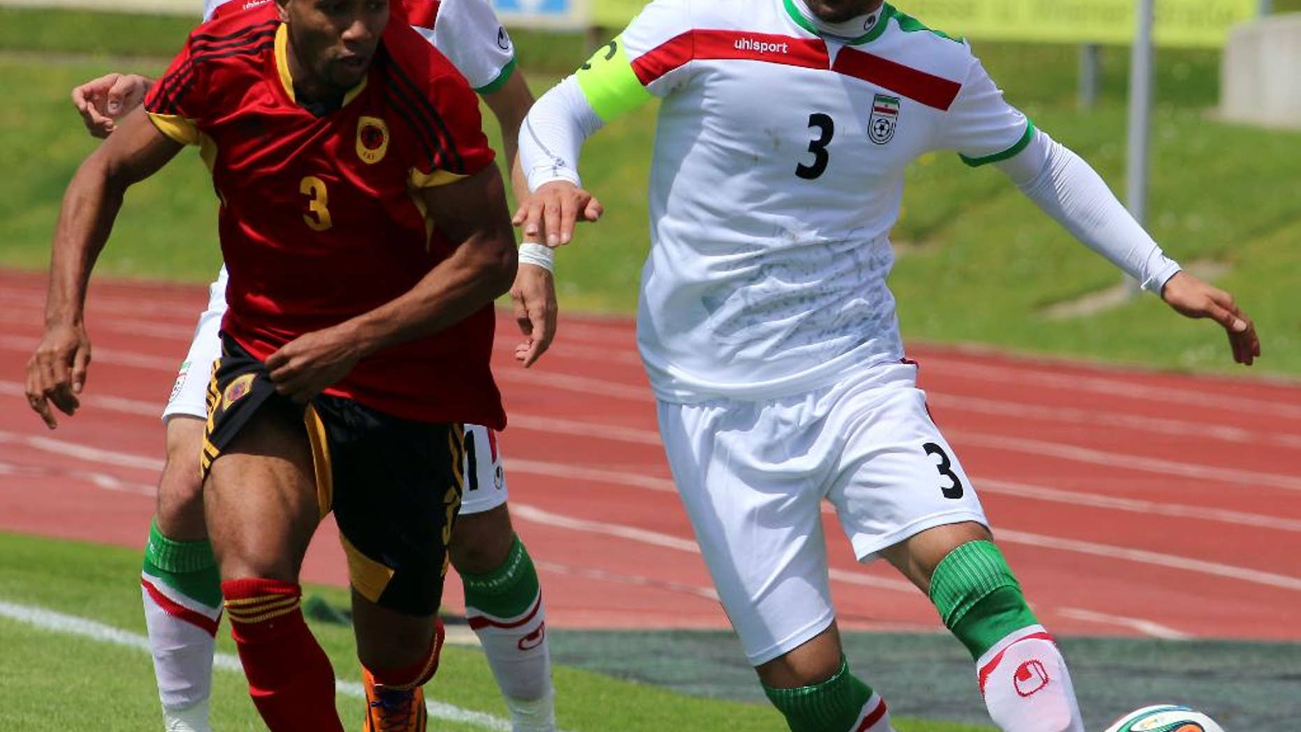 Iran's Ehsan Hajisafi, right, challenges for a ball with Lunguinha, left, of Angola during a friendly soccer match between Iran and Angola, in Hartberg, Austria, Friday, May 30, 2014. (AP Photo/Ronald Zak)