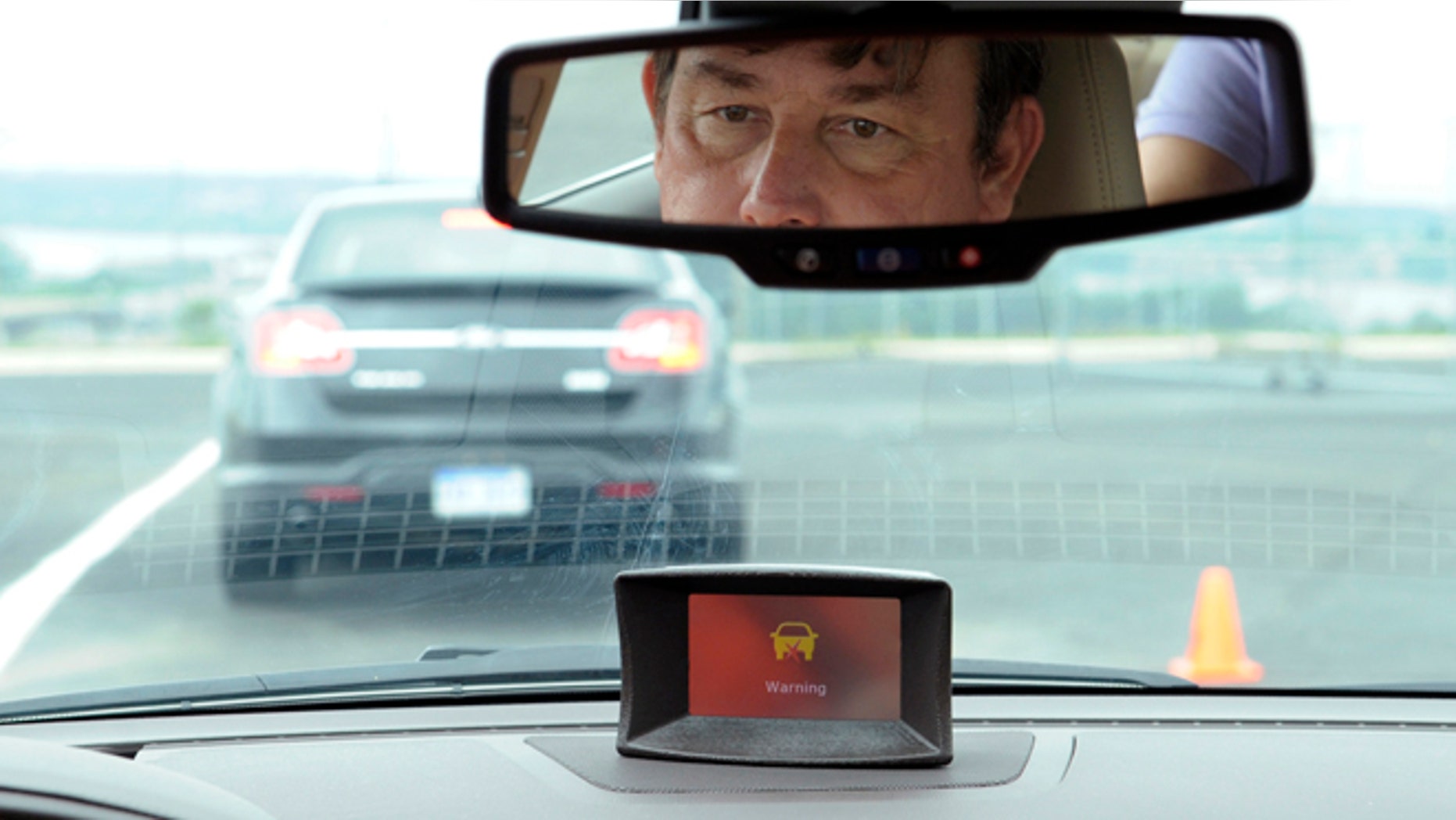 FILE - In this May 22, 2012, file photo,professional test driver Dave McMillan demonstrates the dashboard warning signal in a Buick Lacrosse at an automobile test area in Oxon Hill. The government is speeding up research on safety systems that automatically prevent drivers from operating their cars if they are drunk or aren't buckled properly. Officials also said on Nov. 14, 2013, that they expect to decide by year's end how to encourage automakers to make available in more cars some special safety systems already in certain high-end vehicles. Those systems warn drivers before a collision that they are about to run into another vehicle, and can brake automatically to avoid a crash or make it less severe. (AP Photo/Susan Walsh, File)
