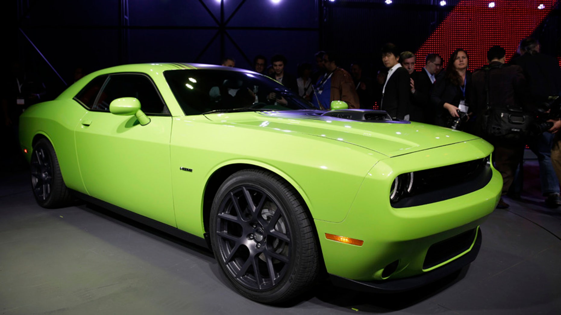 Poeple gather around a 2015 Dodge Challenger after it is introduced at the New York International Auto Show in New York, Thursday, April 17, 2014. (AP Photo/Seth Wenig)