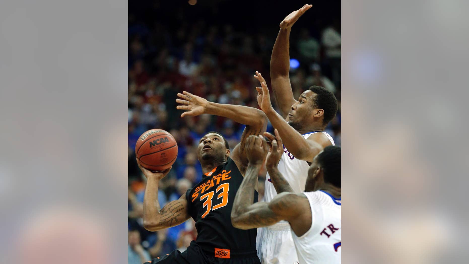 Oklahoma State guard Marcus Smart (33) shoots while covered by Kansas guard Wayne Selden, Jr. (1) and forward Jamari Traylor, right, during the first half of an NCAA college basketball game in the quarterfinals of the Big 12 Conference men's tournament in Kansas City, Mo., Thursday, March 13, 2014. (AP Photo/Orlin Wagner)