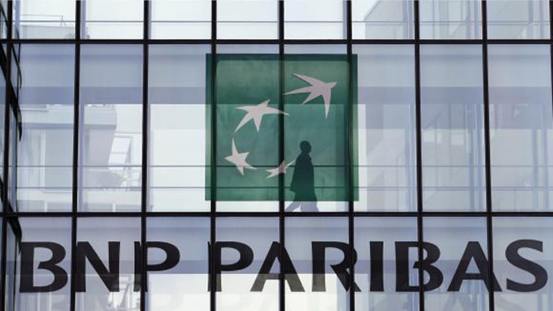 June 2, 2014: An employee walks behind the logo of BNP Paribas in the company's headquarters in Issy-les-Moulineaux, near Paris. (REUTERS/CHARLES PLATIAU)