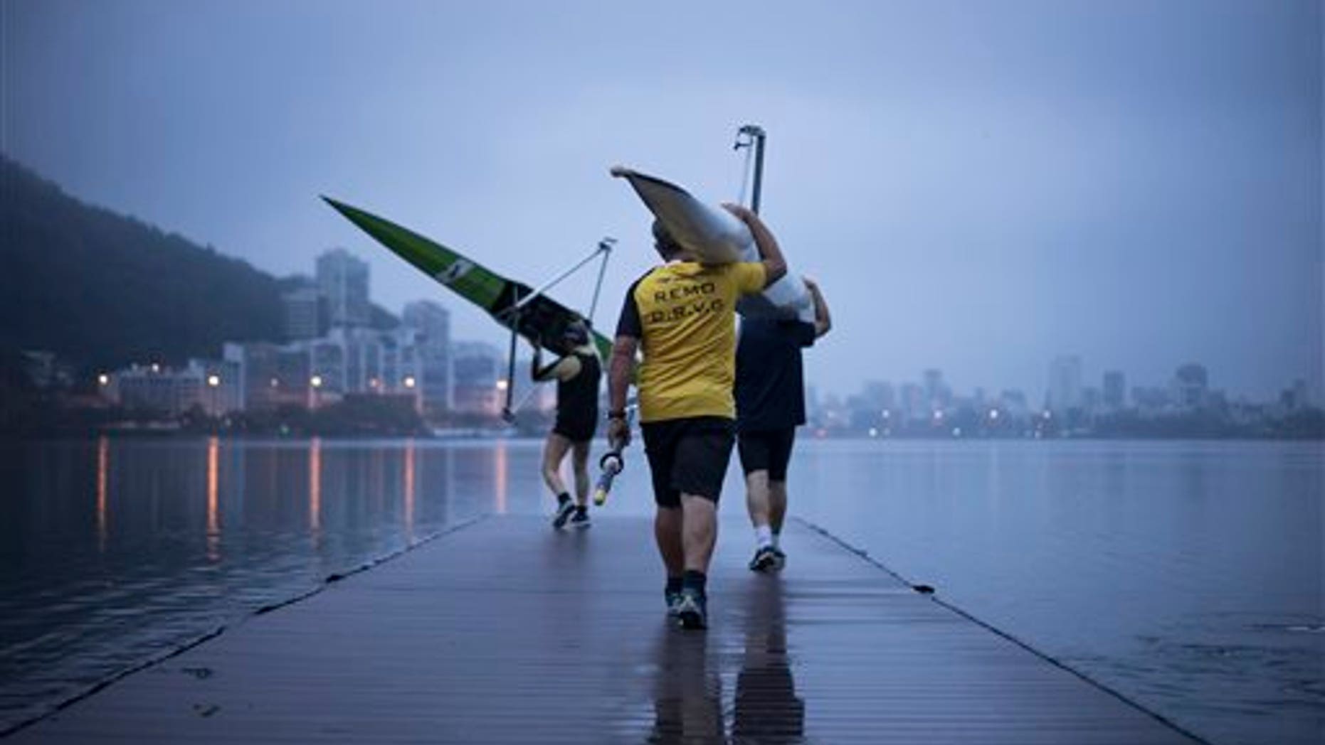 Rowers carry boats at the Rodrigo de Freitas Lagoon in Rio de Janeiro, Brazil, on Nov. 4, 2015. Athletes in Rio test events have tried many tricks and treatments to avoid falling ill from its contaminated waters. (AP Photo/Felipe Dana)