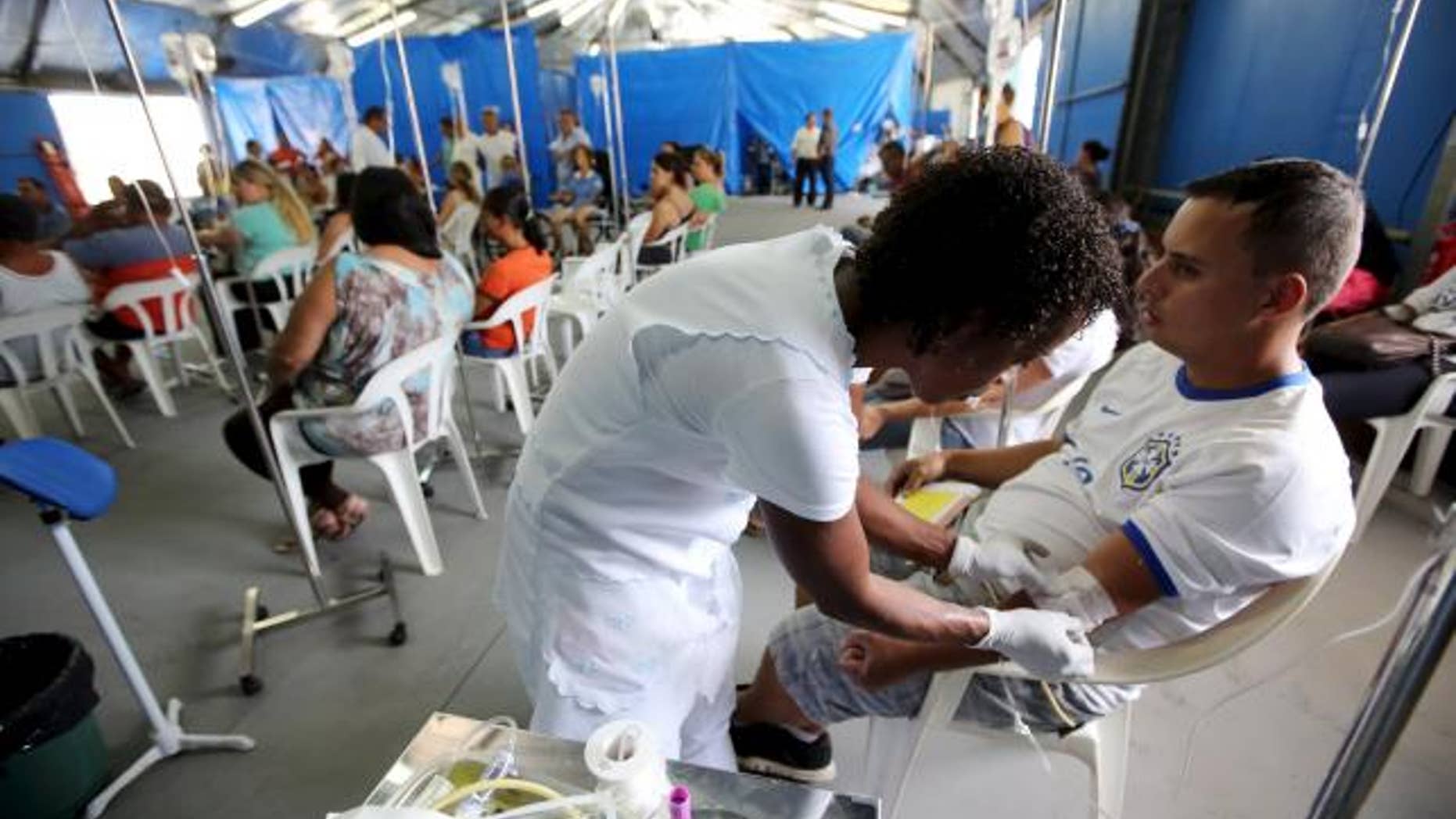 March 5, 2015: A patient is administered drips as he awaits the results of his dengue examination, in a medical tent in Rio Claro, Brazil.