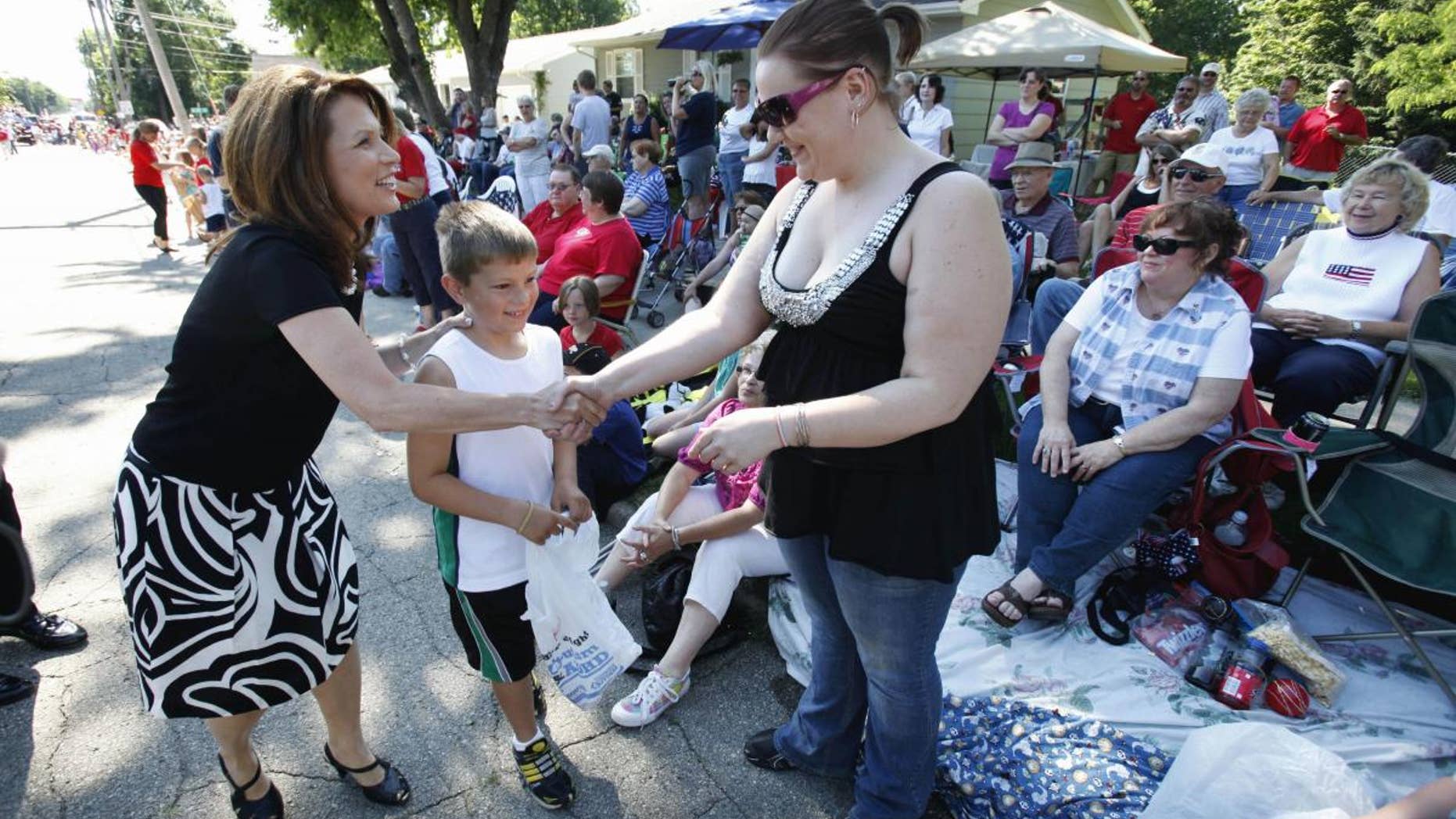 Republican presidential candidate Rep. Michele Bachmann, R-Minn., greets residents while walking in the Fourth of July parade in Clear Lake, Iowa., Monday, July 4, 2011. (AP Photo/Charlie Neibergall)