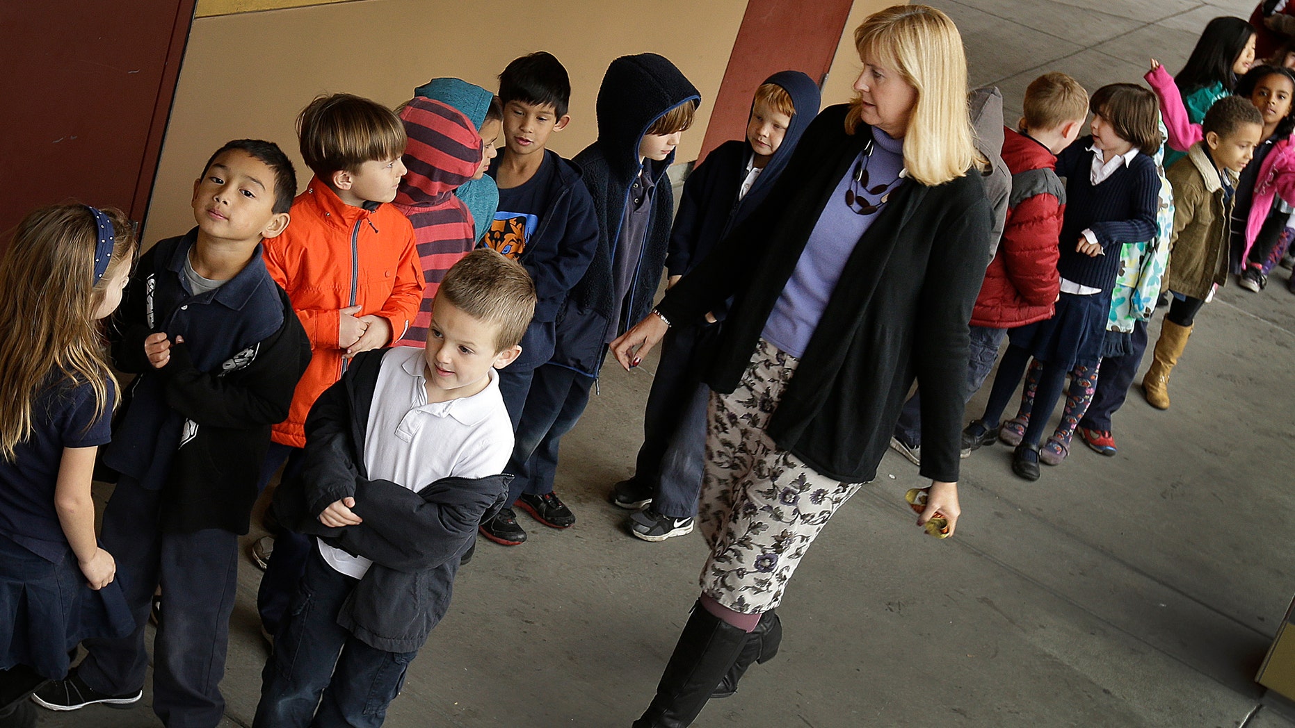 FILE - In this July 24, 2013 file photo, first grade teacher Lynda Jensen walks with her class of 30 children at Willow Glenn Elementary School in San Jose, Calif. Minority and low-income parents are more likely to see serious problems in their schools, from low expectations to bullying and out-of-date technology and textbooks, than those who are affluent or white, according to an Associated Press-NORC Center for Public Affairs Research Poll. The divisions fall along the familiar fault lines of income, education and race that drive so much of American life. (AP Photo/Ben Margot, File)