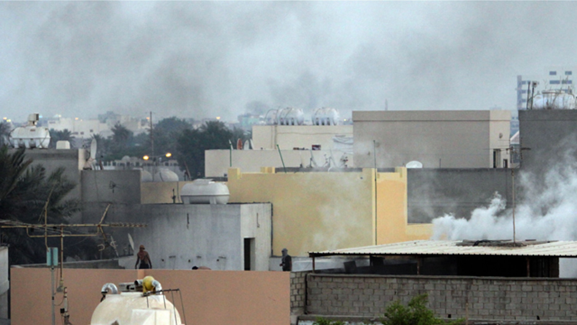Sept. 24: Bahraini protesters move along rooftops as tear gas billows in the Shiite village of Sanabis, Bahrain, during a clash with riot police.