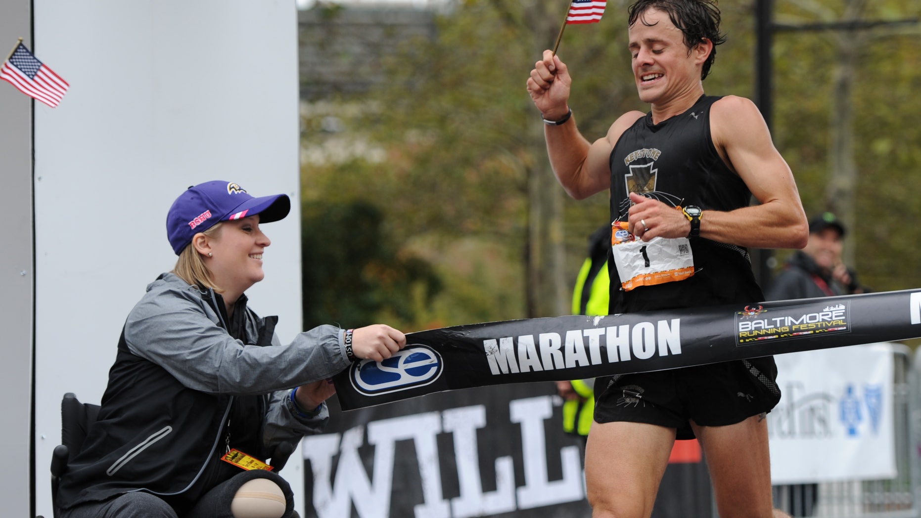 Oct. 12, 2013: Boston marathon bombing survivor Erika Brannock holds an end of the tape at the finish line as runner David Berden wins the Baltimore marathon.