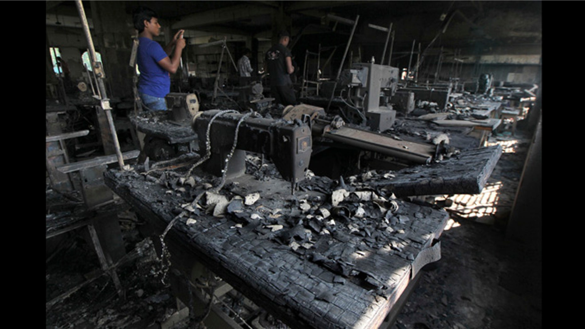 Nov. 26, 2012: A man takes photographs inside a garment-factory where a fire killed more than 110 people Saturday on the outskirts of Dhaka, Bangladesh.
