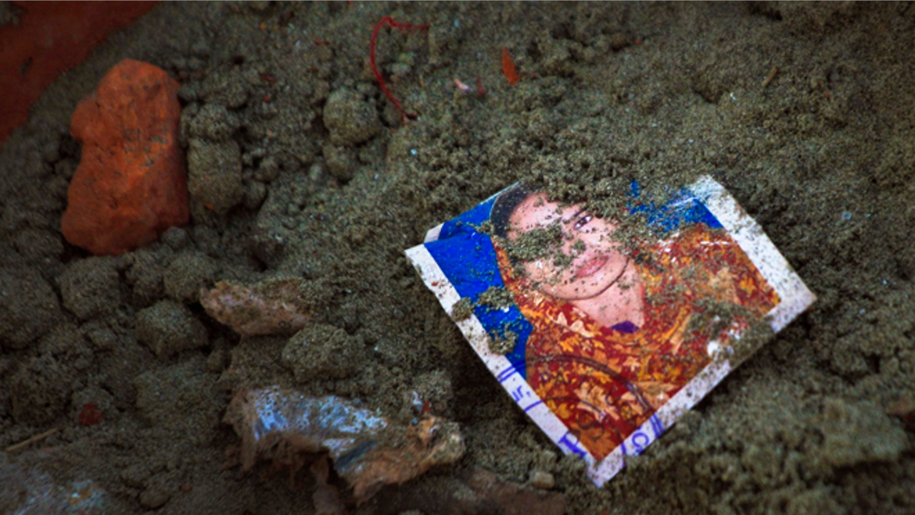 May 5: A photo of a missing garment worker is partially buried in soil at the site of the garment factory building collapse in Savar, near Dhaka, Bangladesh.