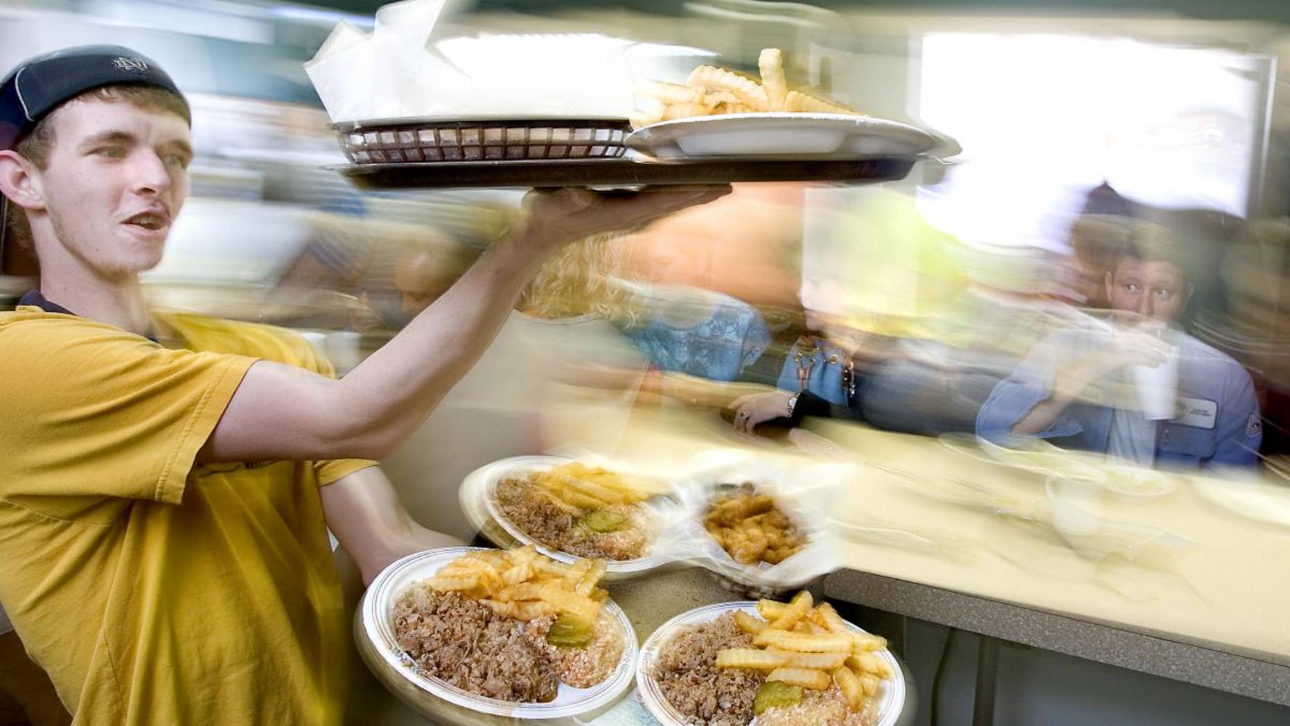 Matthew Hege carries trays of barbecue plates to customers at a barbecue restaurant in Lexington, North Carolina. (AP File Photo/News-Record, H. Scott Hoffmann)