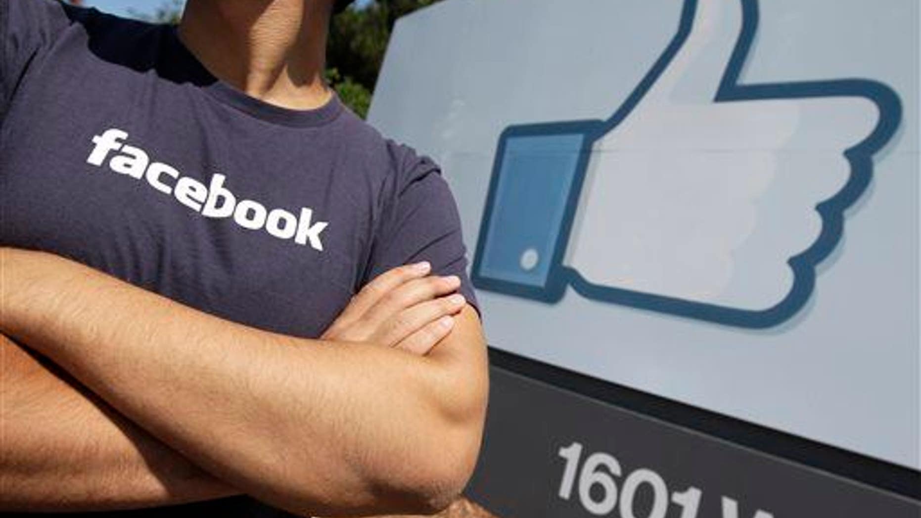 A Facebook worker waits for friends to arrive outside of Facebook headquarters in Menlo Park, Calif.