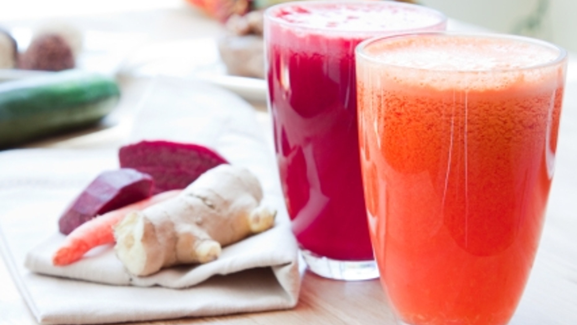 Two glasses of healthy juice - Beet, Apple, Carrot, Ginger and Orange, Apple, Pineapple. Ingredients in the background.