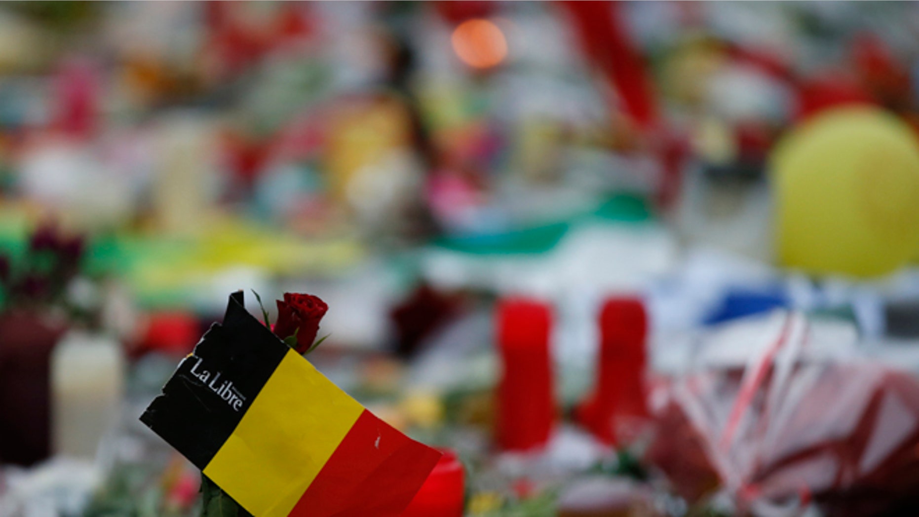 A red rose and the national flag of Belgium amongst the tributes to the victims of the recent attacks in Brussels, placed in the Place de la Bourse in the centre of Brussels, Thursday, March, 24, 2016. Belgium's prime minister is promising to do everything to determine who was responsible for deadly attacks targeting the Brussels airport and subway system. Charles Michel, in a national mourning speech Thursday, said Tuesday's attacks on the European Union's capital targeted the "liberty of daily life" and "the liberty upon which the European project was built."(AP Photo/Alastair Grant)