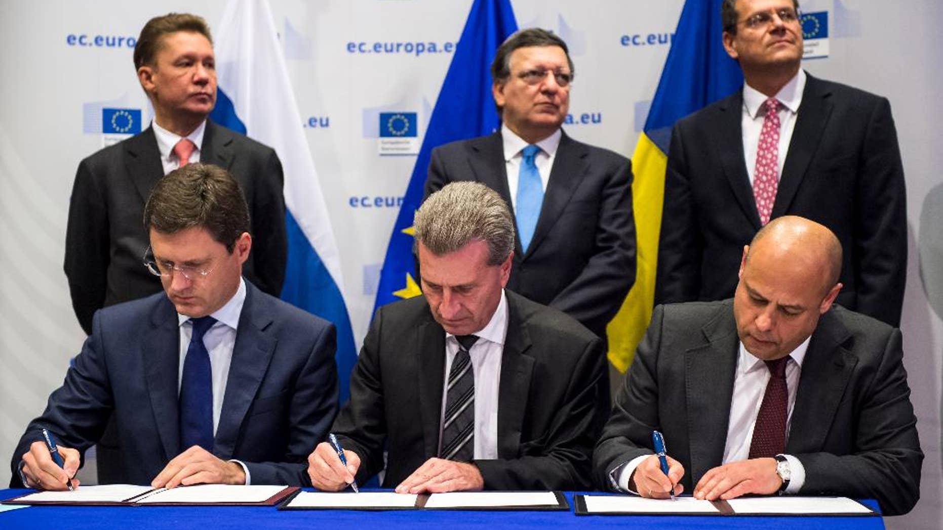 EU Commissioner for Energy Guenther Oettinger, center, Russian Energy Minister Alexander Novak , left, and Ukrainian Energy Minister Yuriy Prodan sign an agreement that guarantees Russian gas will continue to flow to Ukraine and, by extension, parts of the EU this winter as EU Commission President Jose Manuel Barroso, center back, Gazprom CEO Alexey Miller, left back and EU Commissioner for Inter-Institutional Relations and Administration Maros Sefcovic look on, at the European Commission headquarters in Brussels, Thursday, Oct. 30, 2014. (AP Photo/Geert Vanden Wijngaert)