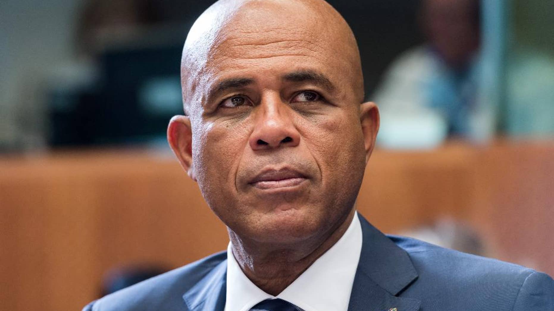 FILE - In this June 10, 2015 file photo, Haiti's President Michel Joseph Martelly waits for the start of a round table meeting at the EU-CELAC summit in Brussels. Hostile comments made by Martelly to a woman at a campaign rally in Haiti have prompted a party in his coalition to remove three officials from his government. Martelly was at a rally in late July 2015 when a woman complained that his government failed to bring electricity to her community. Haitian media reported that he told her in Haitian Creole to “go get a man and go in the bushes” to have sex. (AP Photo/Geert Vanden Wijngaert, File)