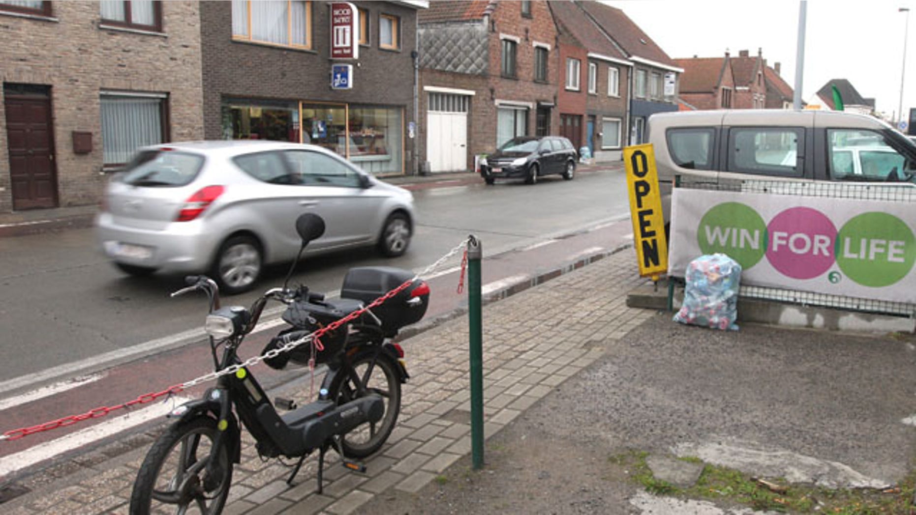 May 2, 2013: A car passes along where robbers lost their cool and threw the vault they had stolen nearby out the car right onto the street causing a 'rainstorm of money', in Zedelgem, western Belgium.