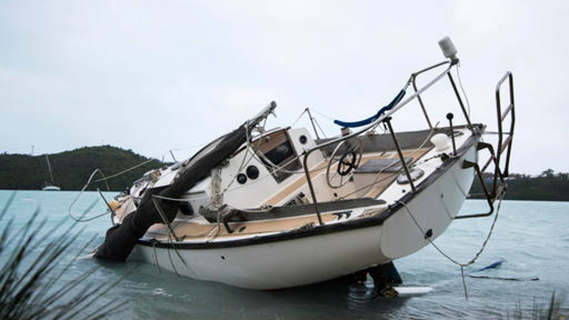 A sailboat lays damaged on the shore of Ferry Reach after breaking free from its mooring after the passing of Hurricane Nicole in St. Georges, Bermuda, Thursday, Oct. 13, 2016. Nicole pummeled the resort island as a Category 3 storm with winds that snapped trees and peeled off roofs before it spun away into open water as a Category 1 storm. (AP Photo/Mark Tatem)
