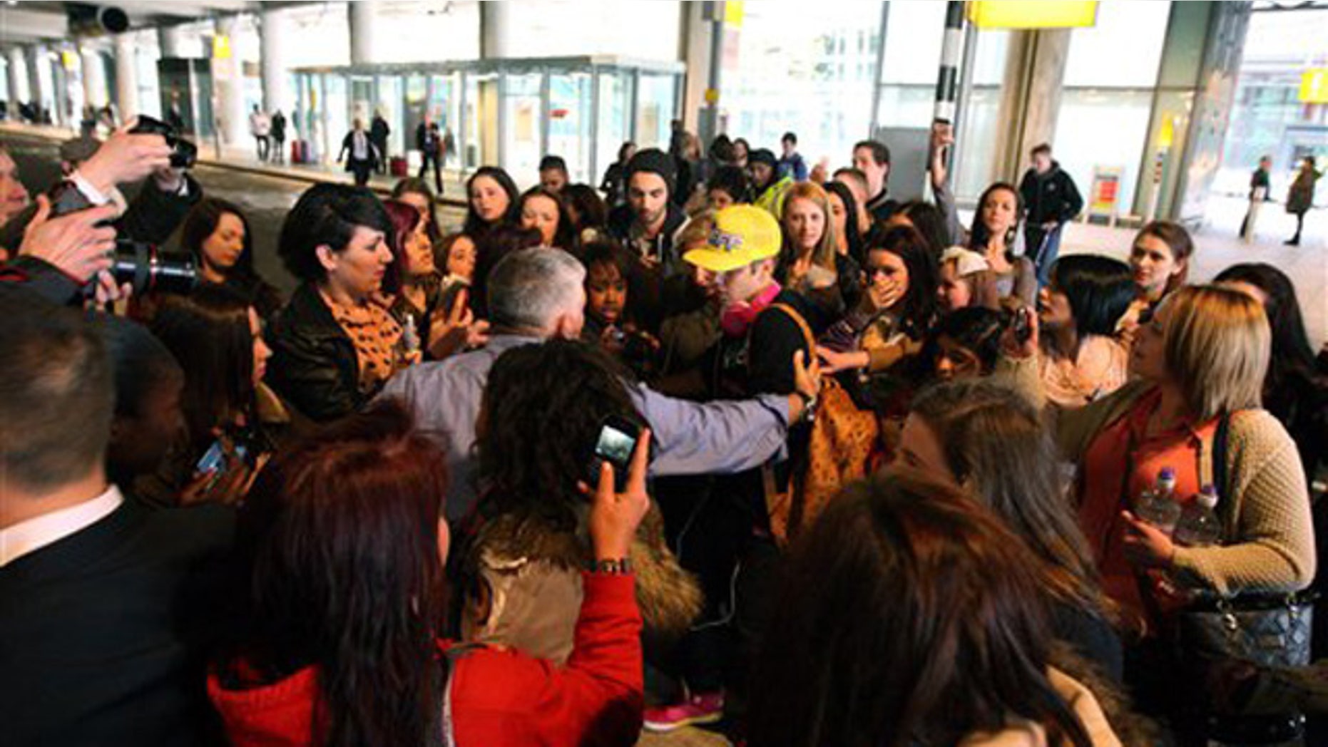 April 23, 2012: Canadian singer Justin Bieber wearing a yellow hat is greeted by fans as he arrives ahead of his album launch at Heathrow Airport, London.