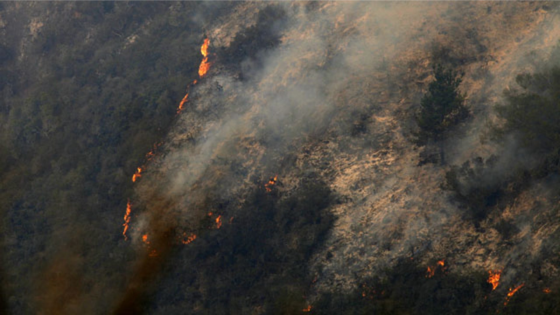 December 17, 2013: Flames creep down a hillside as firefighters battle a fire in the Pfeiffer Ridge area of Big Sur, Calif. Firefighters are making gains against the unusual fall wildfire that has destroyed 15 homes and forced about 100 people to flee the forested mountains of California's scenic Big Sur region overlooking the Pacific. (AP Photo)