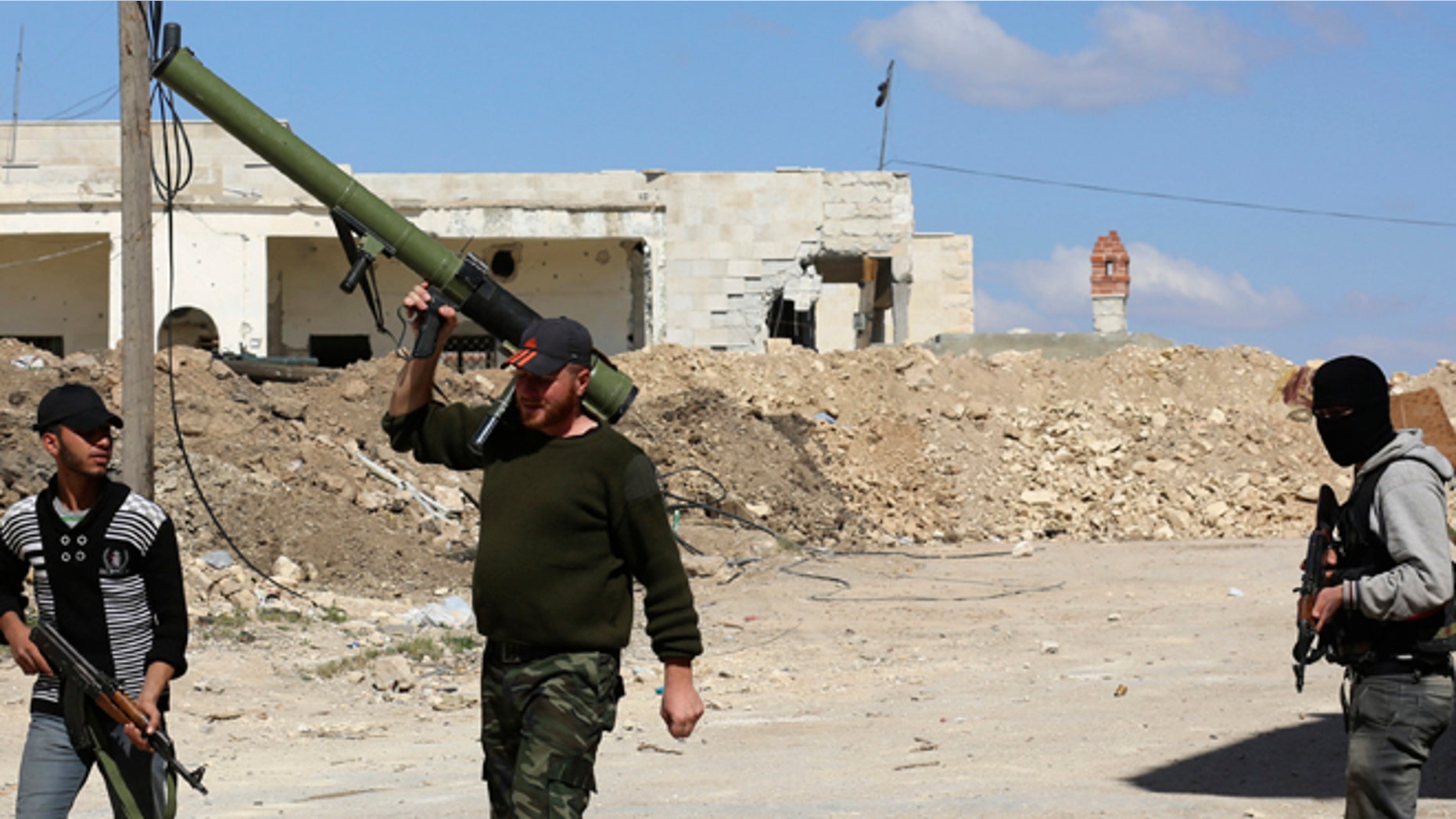 April 9, 2014: Rebel fighters carry their weapons as they walk along a street in the town of Morek in Hama province.