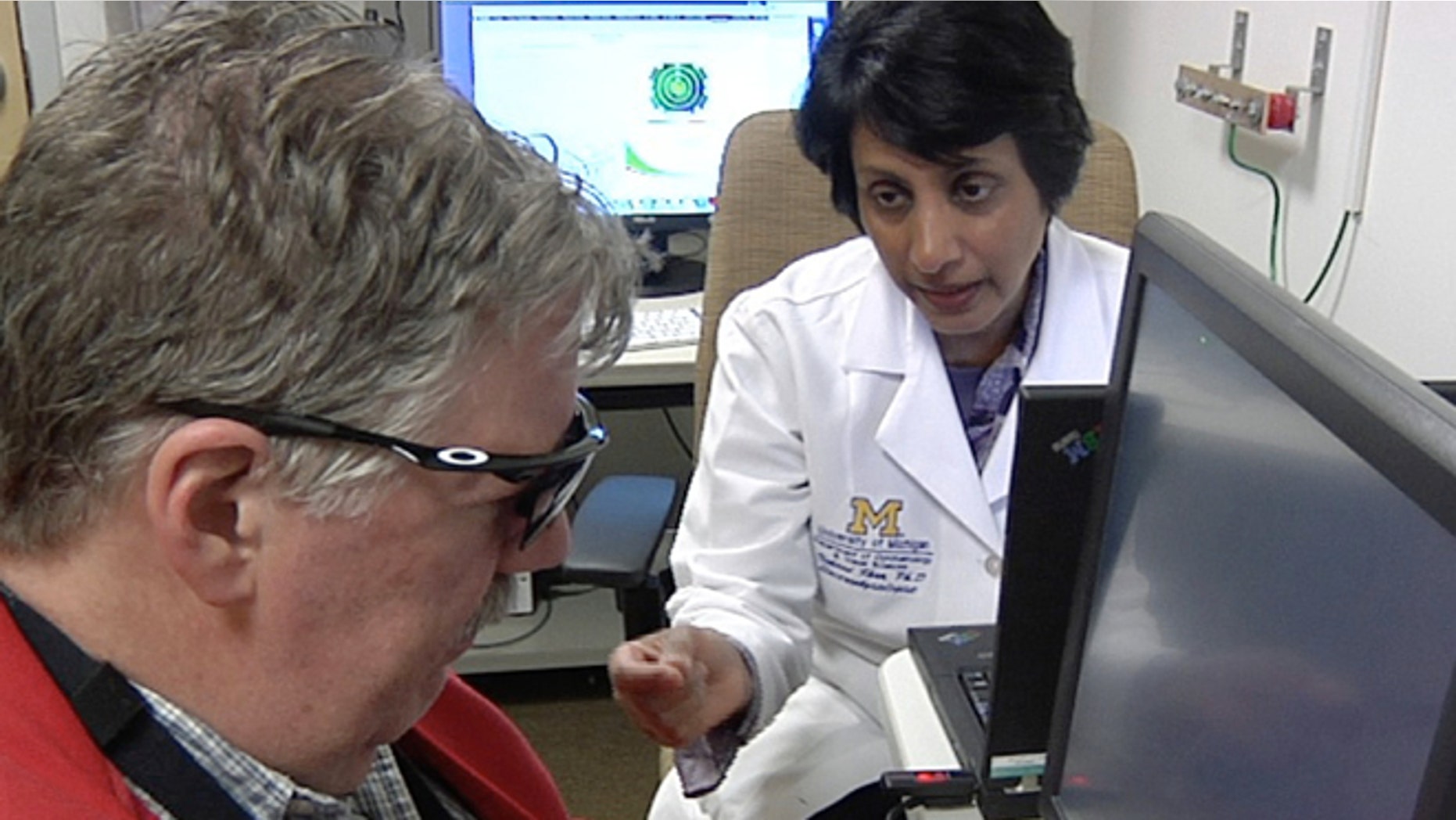 In this April 16, 2014 image from video Dr. Naheed Khan, right, works with Roger Pontz, left, on an exercise to test how well he sees shapes on a computer screen at the University of Michigan Kellogg Eye Center, April 16, 2014, in Ann Arbor, Mich. Pontz suffers from a degenerative eye disease called retinitis pigmentosa and is the second patient in the U.S. to surgically receive a bionic eye since the U.S. Food and Drug Administration signed off on its use last year. (AP Photo, Mike Householder)