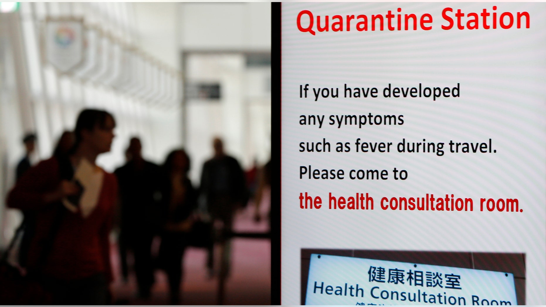 A passenger from China walks behind a signboard toward the quarantine station at Haneda international airport in Tokyo.