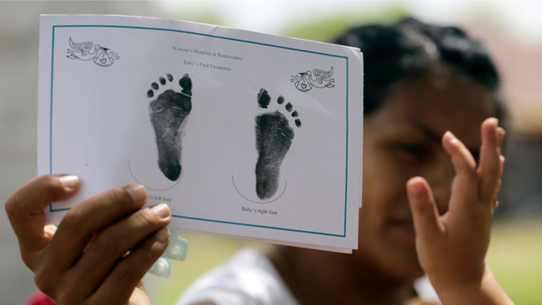 In this Sept. 16, 2015, photo, a woman in Sullivan City, Texas, who said she entered the country illegally shows the footprints of her daughter, reaching into photo, who was born in the United States, but was denied a birth certificate. Texas has for seven years said it wonât accept Mexican identification cards when issuing birth certificates for children of people in the United States illegally. But it doesnât appear to have stepped up enforcement until recently, amid mounting political pressure to get tougher on immigration, documents obtained by The Associated Press show. (AP Photo/Eric Gay)
