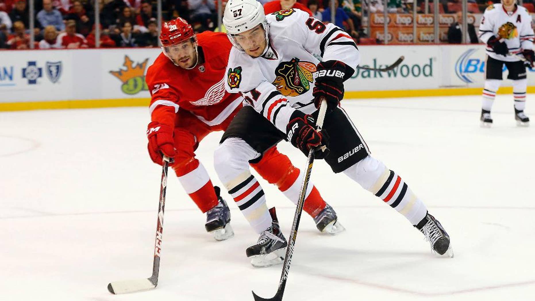 Detroit Red Wings left wing Drew Miller (20) defends Chicago Blackhawks defenseman Trevor van Riemsdyk (57) in the first period of an NHL hockey game in Detroit, Friday, Nov. 14, 2014. (AP Photo/Paul Sancya)