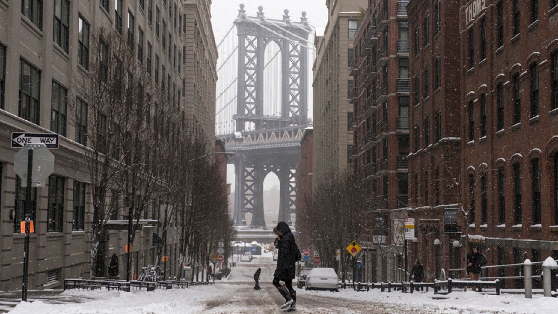 The Manhattan Bridge is seen in the background as commuters make their way through the streets of Dumbo after a snow storm in New York Jan. 27, 2015.