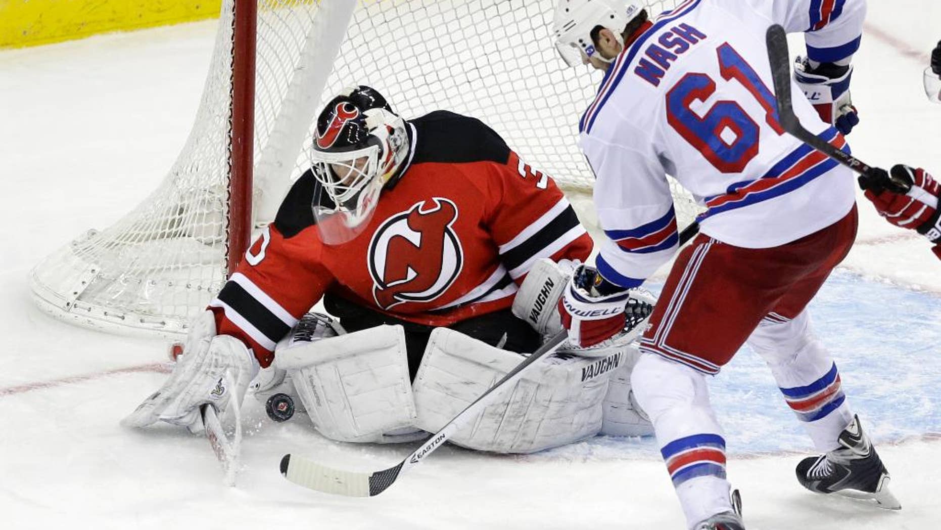 FILE - In this March 22, 2014, file photo, New Jersey Devils goalie Martin Brodeur (30) stops a shot by New York Rangers' Rick Nash (61) during the third period of an NHL hockey game in Newark, N.J. Brodeur wasn't ready to call it a career at 42 after the Devils chose not to re-sign him. But he didn't get any offers until Blues general manager Doug Armstrong called Brodeur's agent on Tuesday, Nov. 25, after goalie Brian Elliott sustained a lower-body injury in the Blues' 3-2 shootout loss to the Ottawa Senators. Brodeur, who leads the NHL in wins (688), games played (1,259), losses (394) and shutouts (124), took part in the morning skate Friday with the Blues, who will face the Edmonton Oilers. (AP Photo/Mel Evans, File)