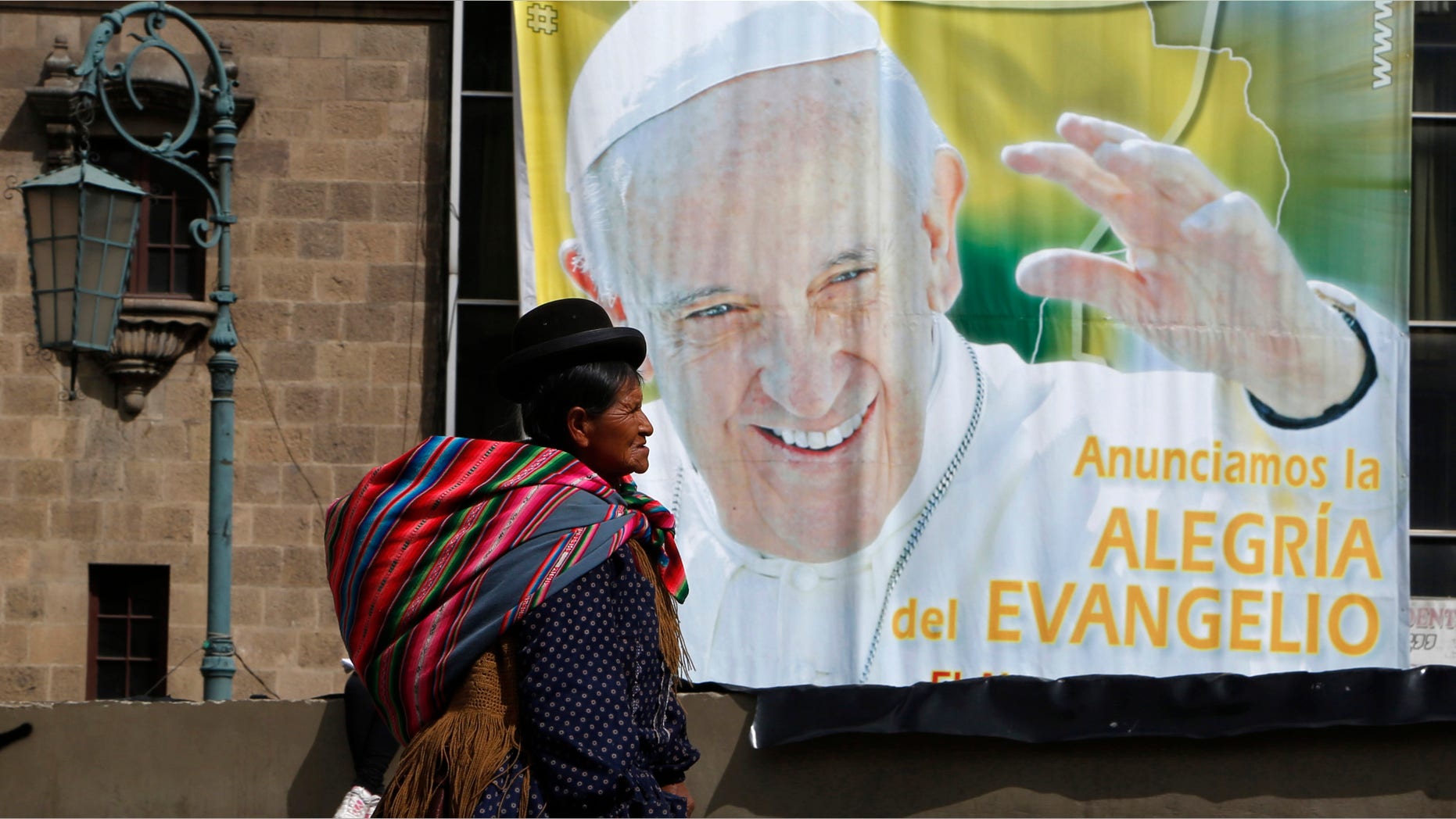 An Aymara indigenous woman walks past a billboard featuring Pope Francis with a message that reads in Spanish: "Announcing the joy of the Gospel" in La Paz, Bolivia, Friday, July 3, 2015. The pope's trip to South America that includes Bolivia is set for July 5-12, though he will only spend four hours in Bolivia's capital due to the altitude, church officials say. (AP Photo/Juan Karita)