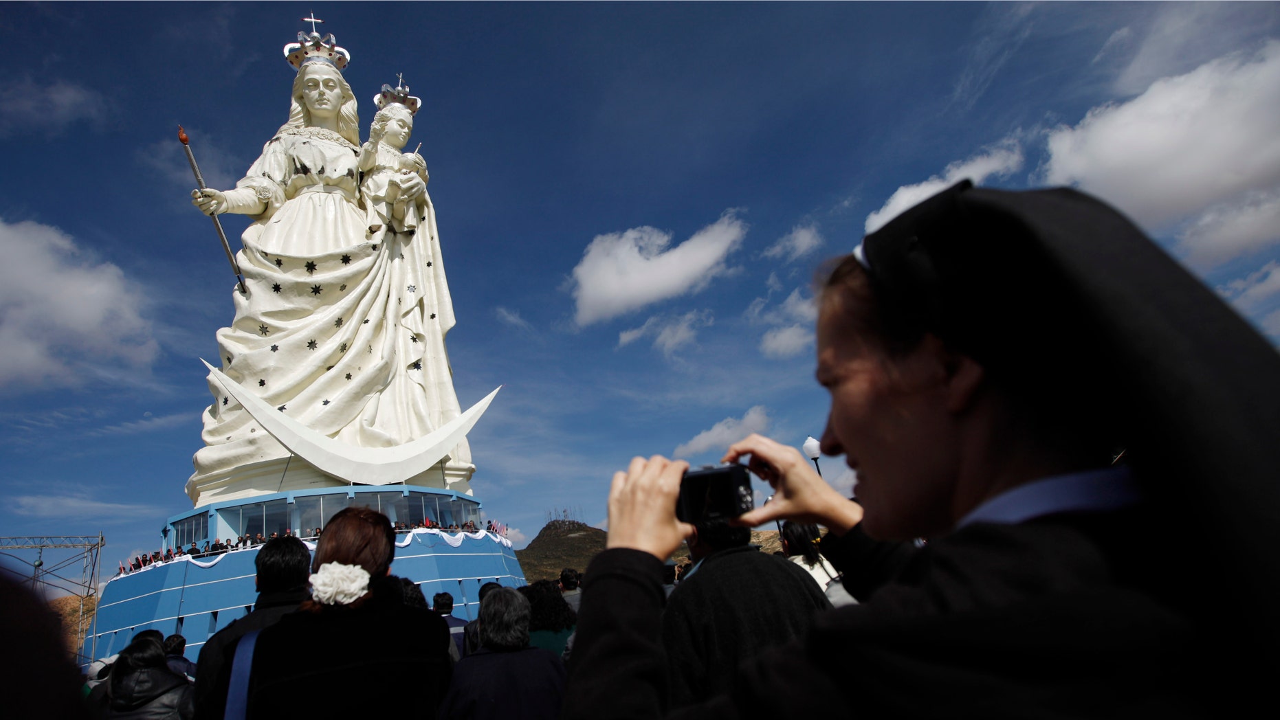 A nun takes pictures of a newly unveiled statue of the Virgin Mary holding a baby Jesus on Santa Barbara hill in the mining city of Oruro, Bolivia. The 45 meter (147 feet) statue that took four years to build, known in Spanish as "Virgen del Socavón," or the Virgin of the Tunnel, is Oruro's patron, venerated in particular by miners and folkloric Carnival dancers. (AP Photo/Juan Karita)