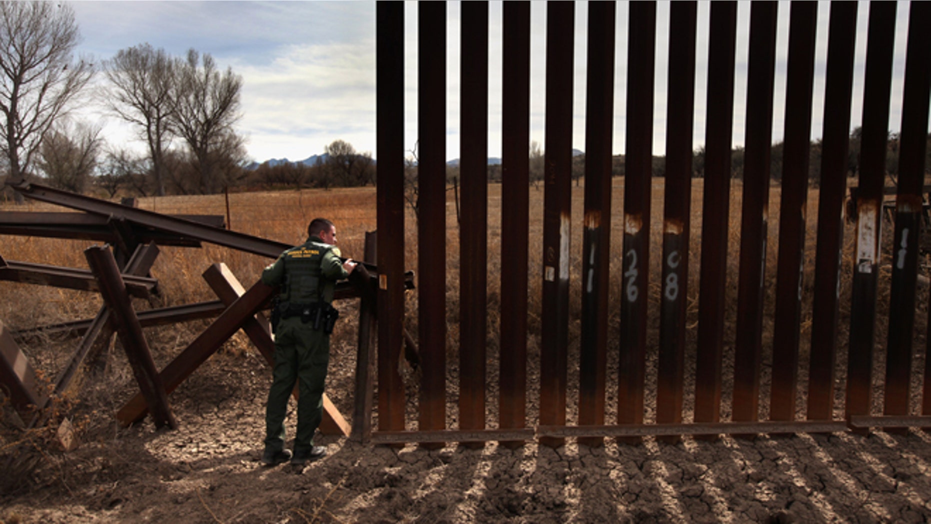 U.S. Border Patrol agent Richard Funke inspects the juction of the new and old border fence at the U.S.- Mexico border on December 7, 2010 near Nogales, Arizona. (Photo by John Moore/Getty Images)