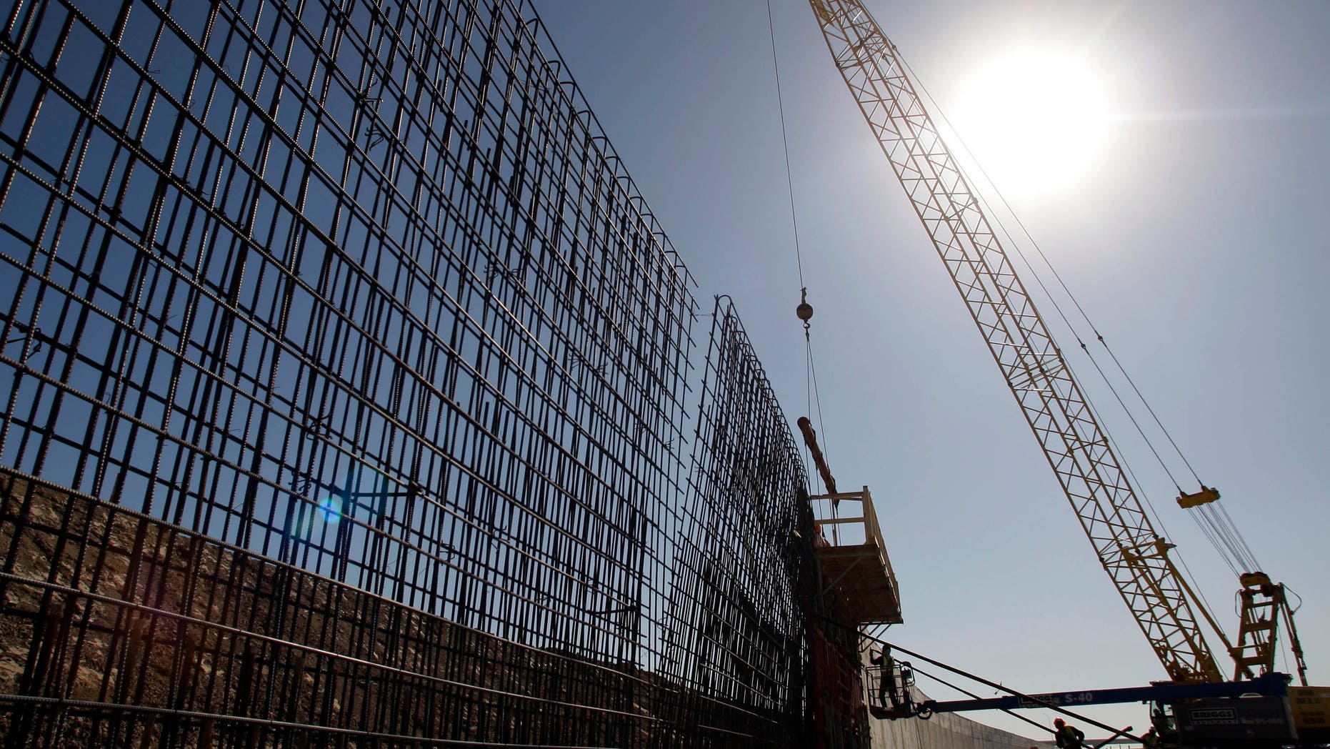 File - In this Feb. 4, 2009 file photo, the sun beats down on construction workers constructing the border wall in Granjeno, Texas. If Congress agrees on a comprehensive immigration reform bill, it will probably include a requirement to erect fencing that would wrap more of the nation's nearly 2,000-mile Southwest border in tall steel columns. But the mandate would essentially double down on a strategy that the Customs and Border Protection agency isn't even sure works. (AP Photo/Eric Gay, File)
