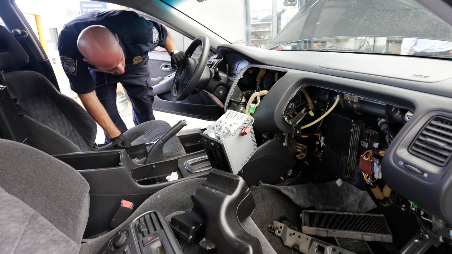 June 27, 2013: Customs and Border Protection officer Steve Delgado looks in at the dismembered dashboard of a Honda Accord after finding more than 14 pounds of methamphetamine hidden behind the radio at the San Ysidro port of entry in San Diego.