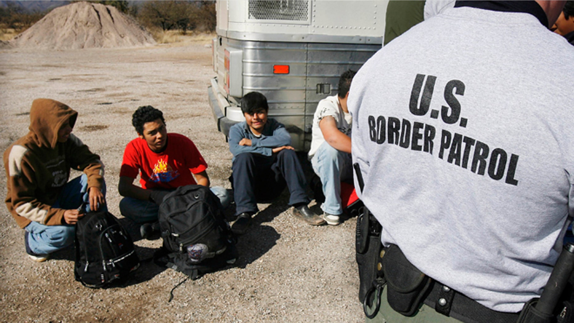 FILE - In this Jan. 19, 2007 file photo, the U.S. Border Patrol detains a large group of suspected immigrants at the Arizona-Mexico border in Sasabe, Ariz. A federal judge has barred use of a policy that allowed people who paid to be sneaked into the United States to be charged under Arizonaâs immigrant smuggling law as conspirators to the crime. U.S. District Judge Robert Broomfieldâs ruling said the interpretation of the 2005 state law conflicts with federal law. The ruling is the latest in a series of restrictions placed on Maricopa County Sheriff Joe Arpaioâs immigration enforcement efforts. (AP Photo/Ross D. Franklin, File)