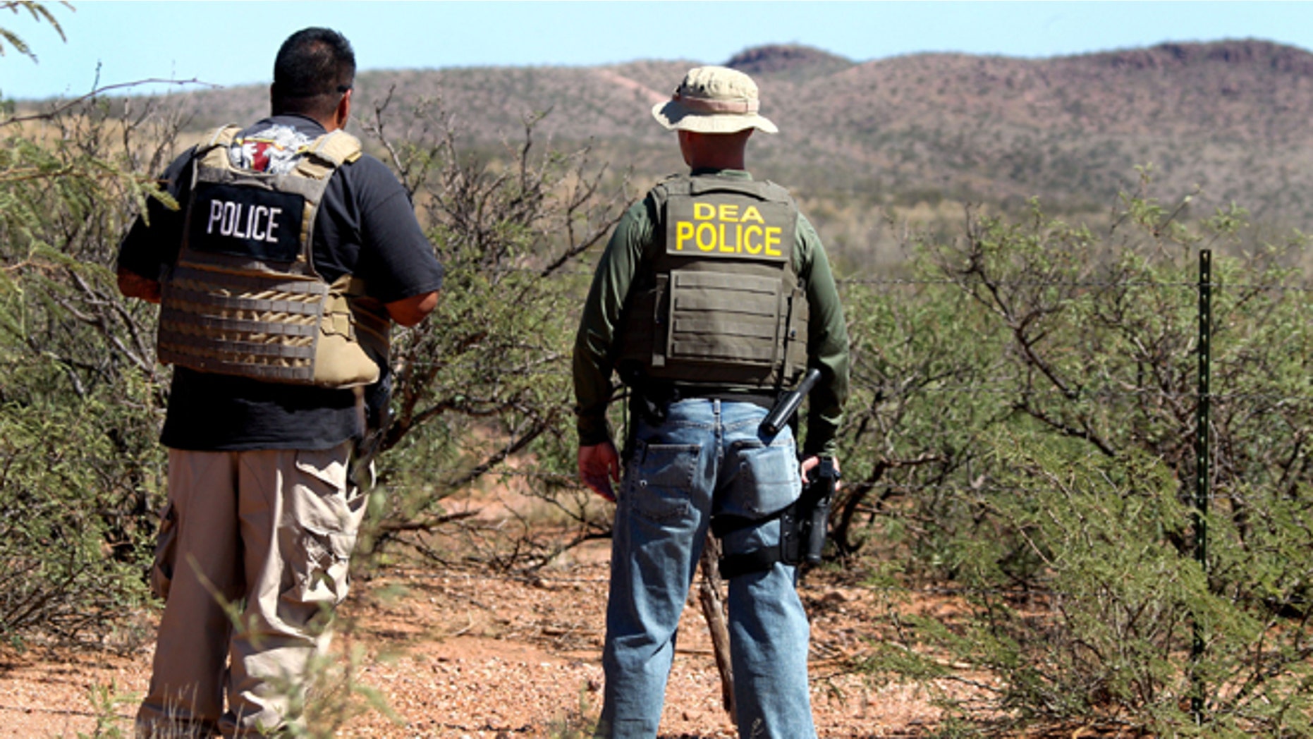 Det. Bill Silva, left, with the Bisbee Police Department, and an unnamed agent with the Drug Enforcement Administration patrol a fence line east of Naco, Ariz., after a Border Patrol agent was killed early Tuesday, Oct. 2, 2012. The shooting occurred after an alarm was triggered on one of the thousands of sensors placed by the U.S. government along the border, and the agents went to investigate, said Cochise County Sheriff's spokeswoman Carol Capas. (AP Photo/Arizona Daily Star, Mike Christy) NO MAGS NO SALES, MANDATORY CREDIT